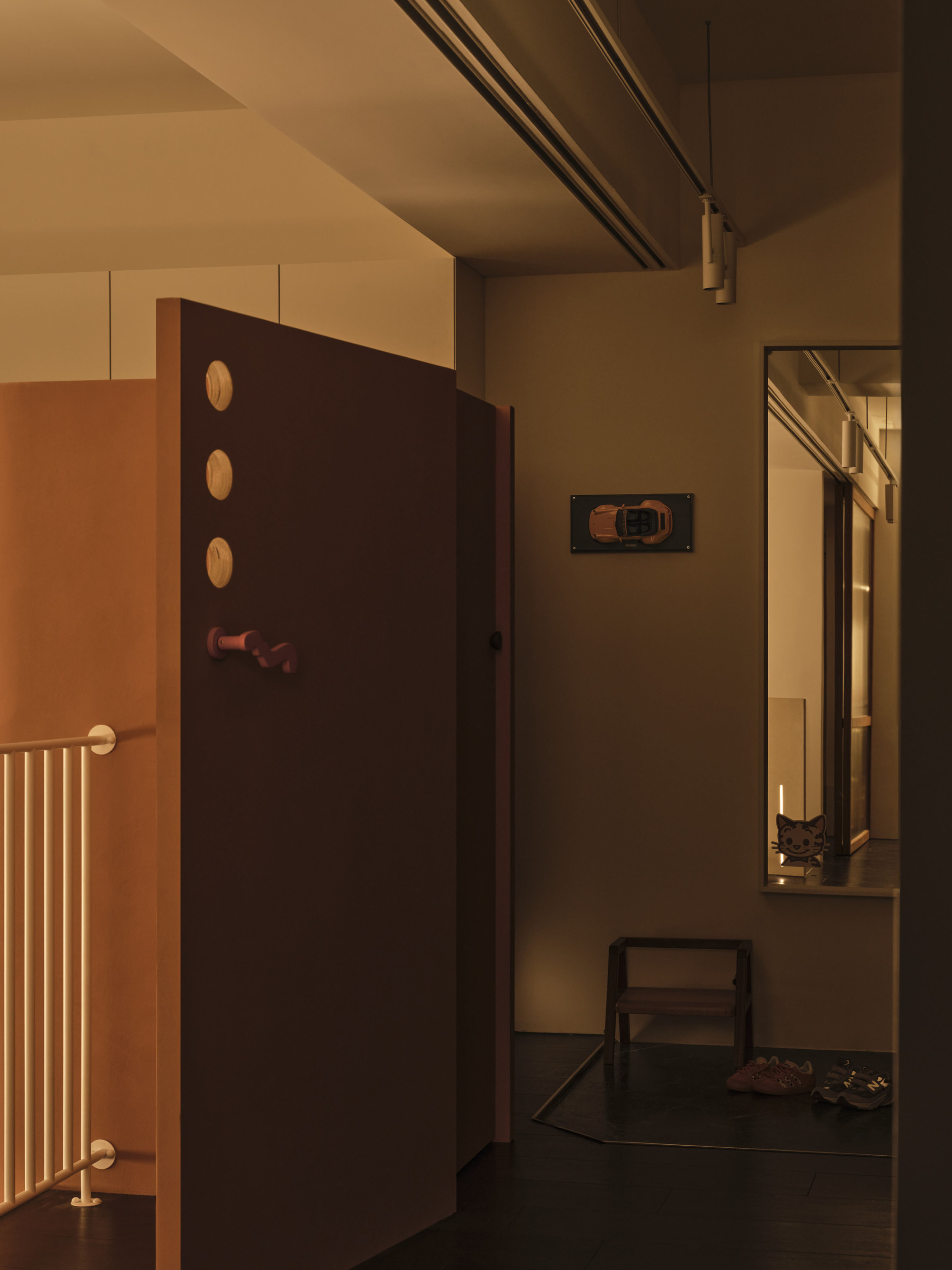 Interior hallway corner showing dark wall with circular openings and a tall mirror reflecting the passage