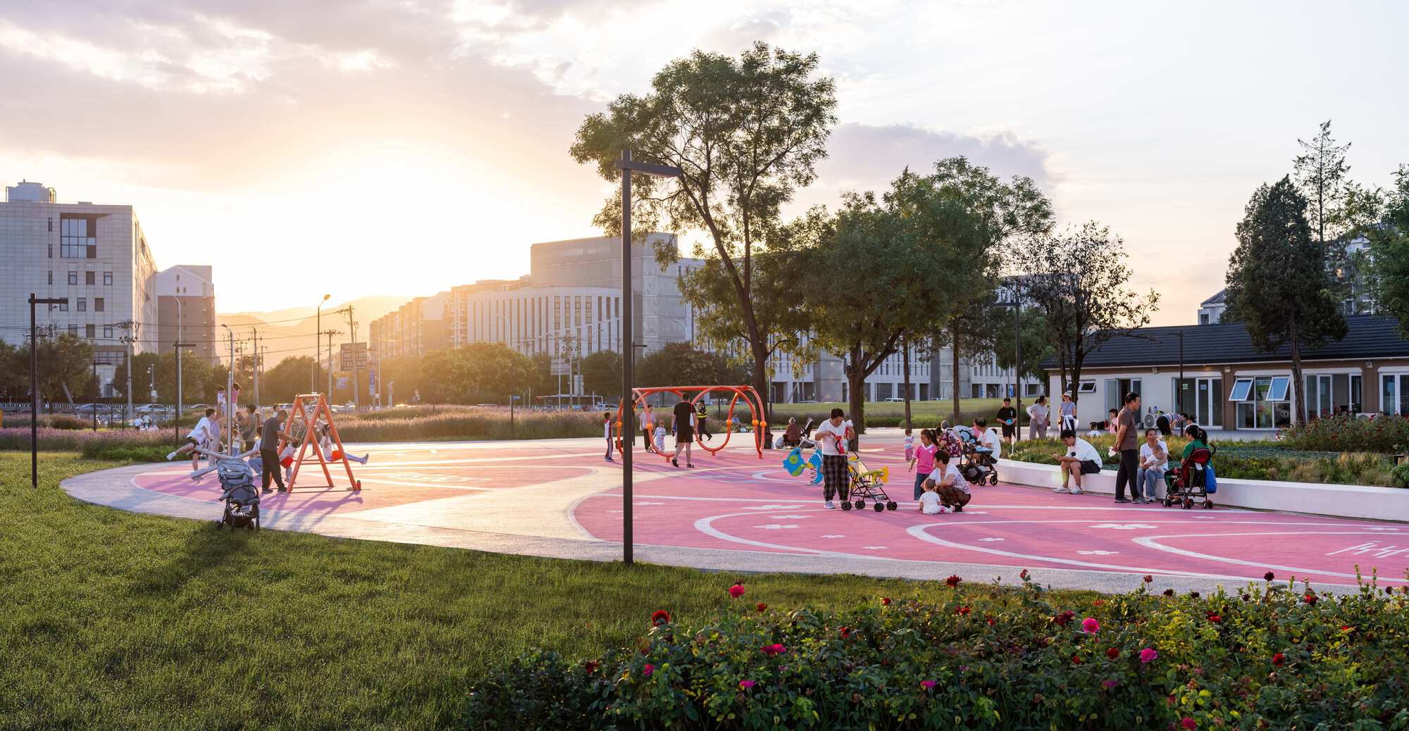 Pink circular play surface with white curved seating edge and children playing at sunset