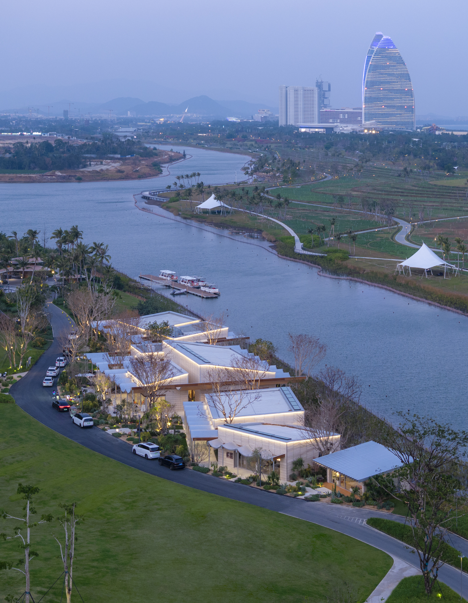 Elevated twilight view of pavilions lining the canal with mountains and towers in the distance