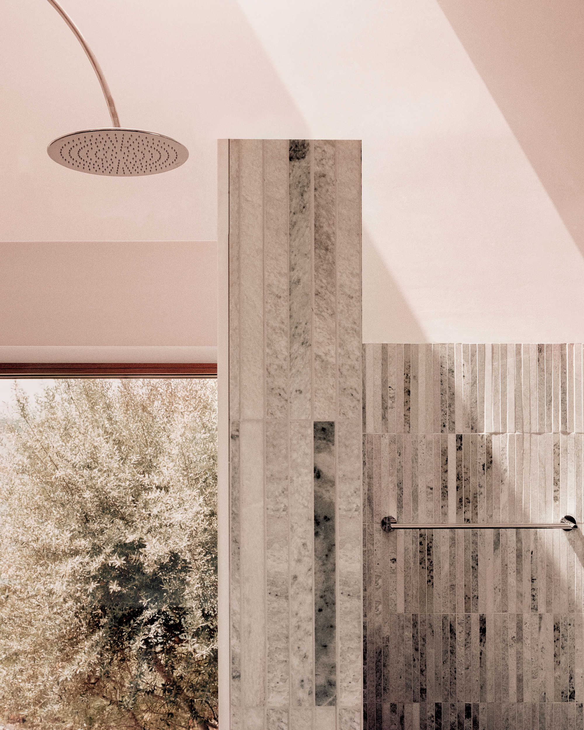 Bathroom with vertical stone tile wall and curved plaster ceiling beneath a skylight