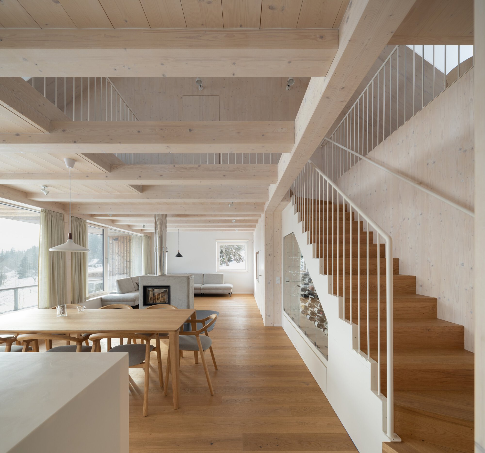 Open living space with exposed timber beams and wooden staircase with vertical slat balustrade