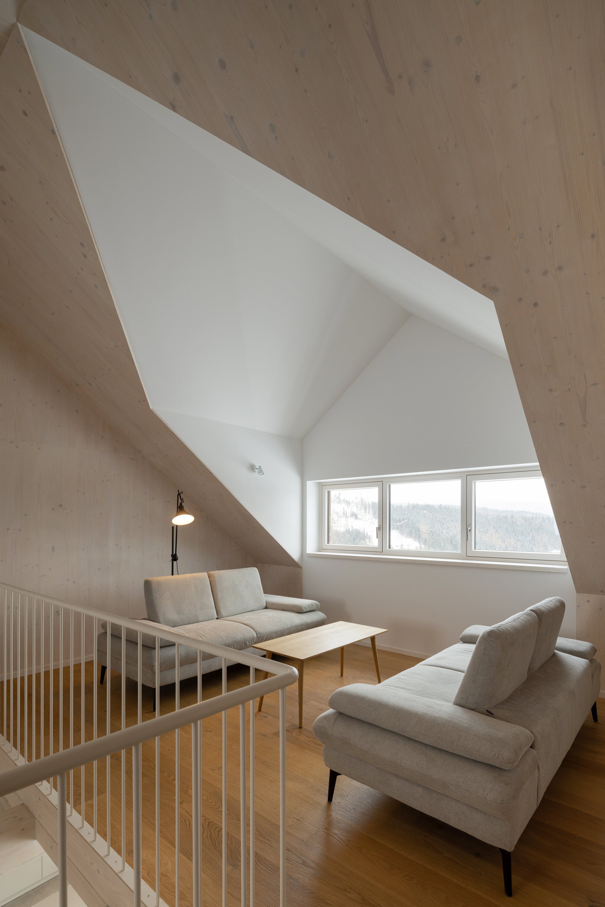 Upper floor sitting area with angled ceiling cutout and timber balustrade overlooking the floor below
