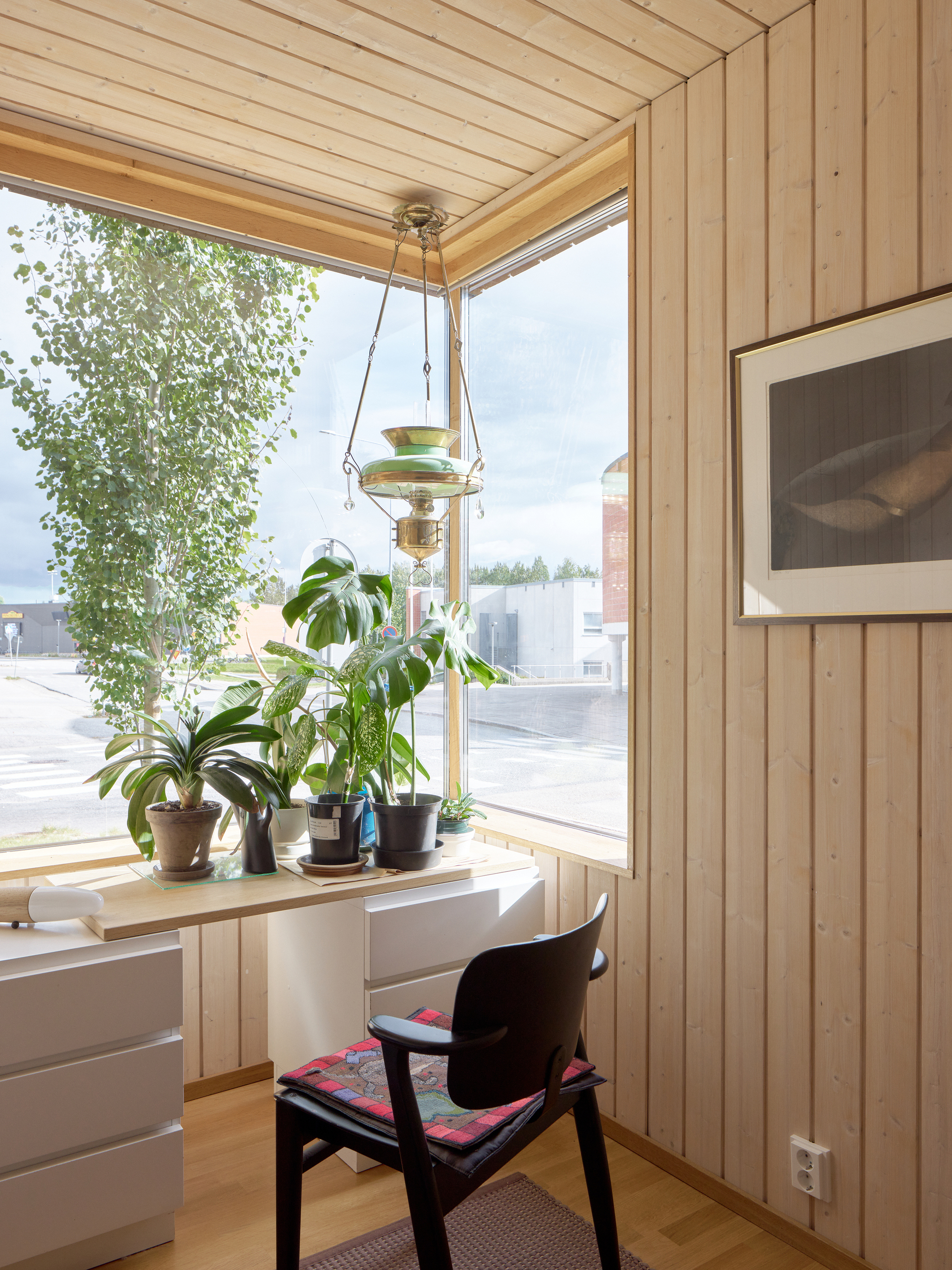 Corner workstation with vertical timber cladding and a row of potted plants on the sill