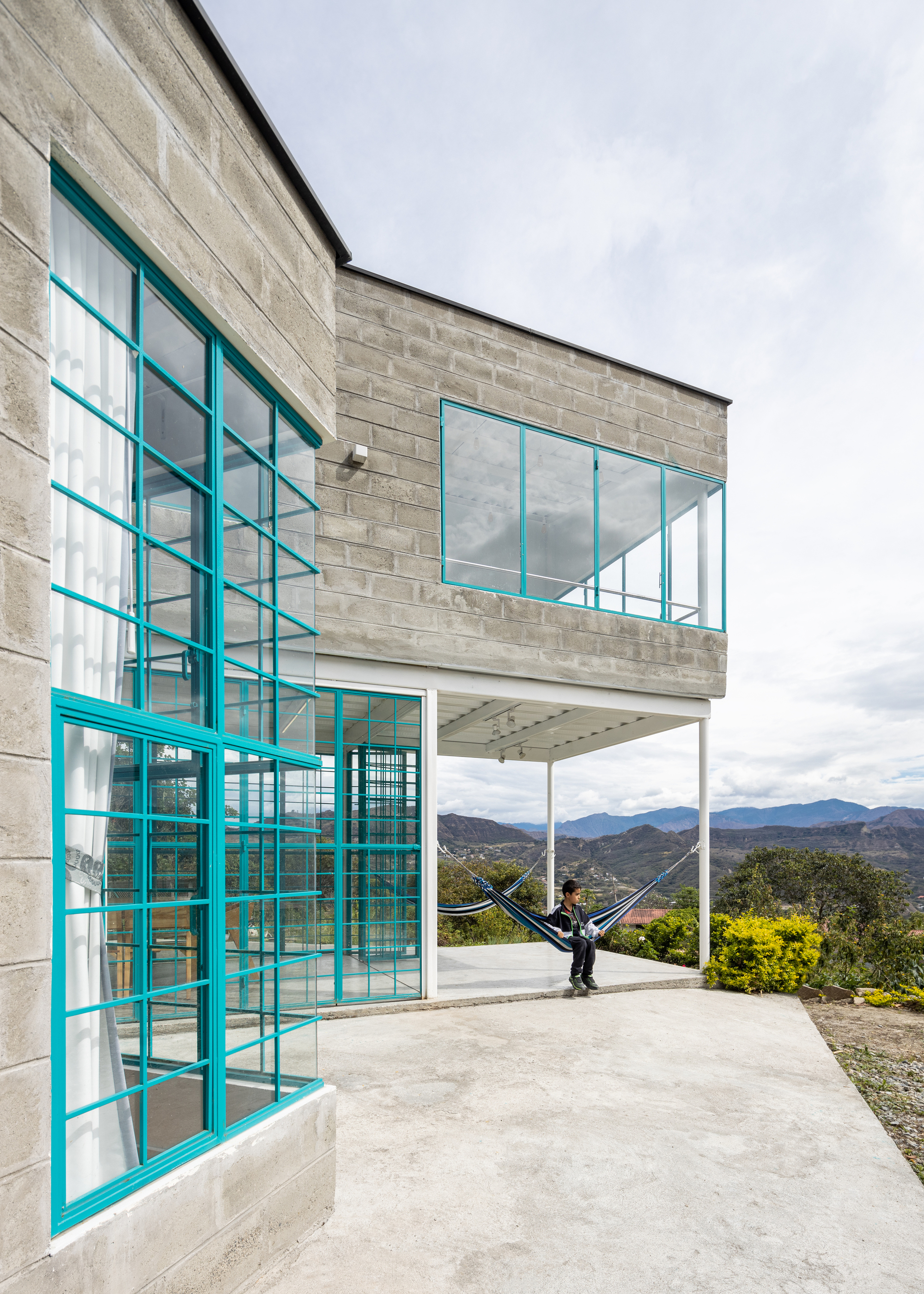 Corner terrace with turquoise steel frames and a person in a hammock overlooking distant mountains