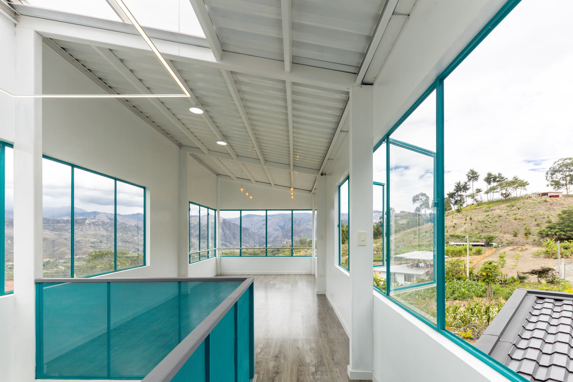 Interior corridor with turquoise glass balustrade and panoramic windows framing the valley landscape