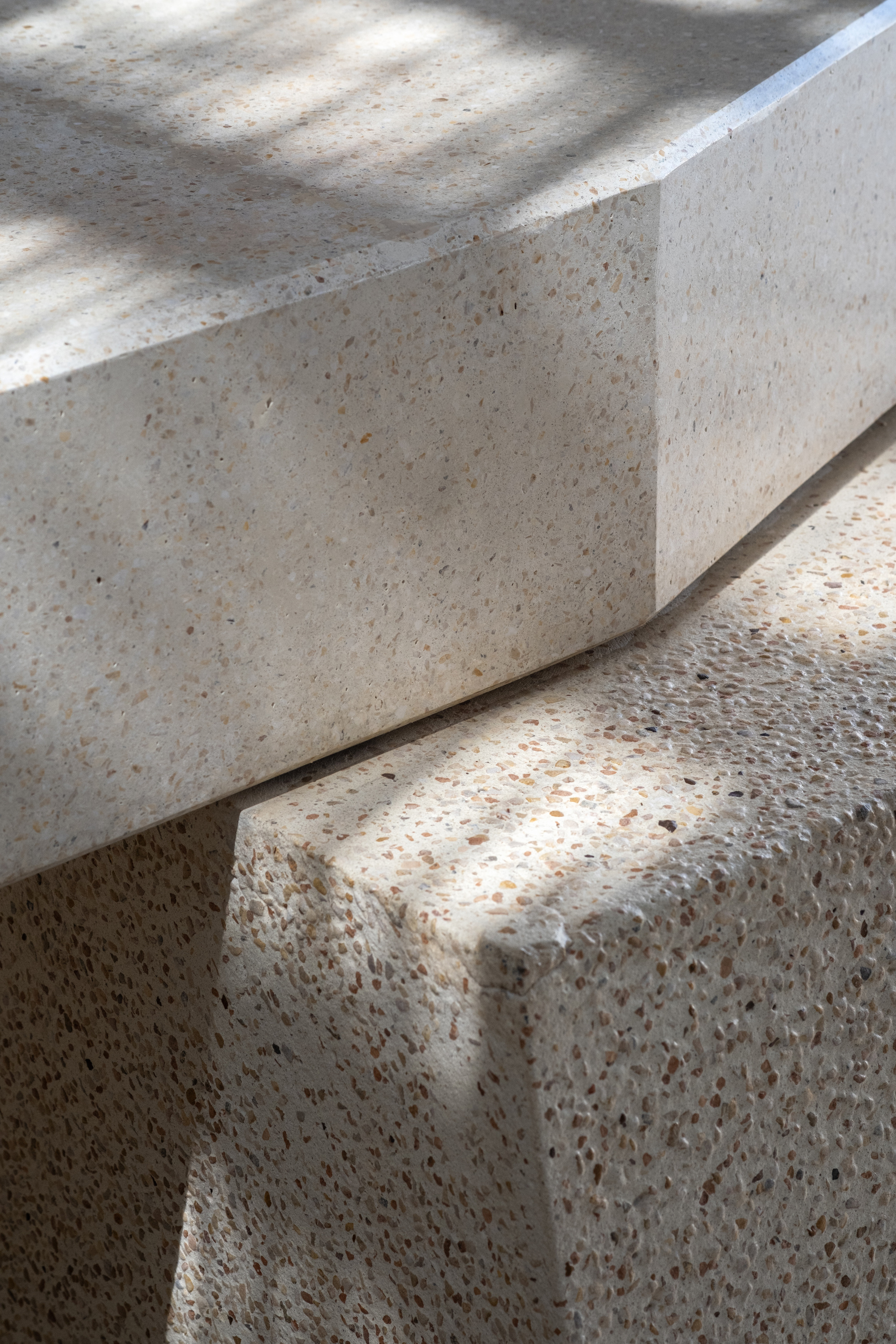 Detail of terrazzo steps with exposed aggregate finish in dappled natural light
