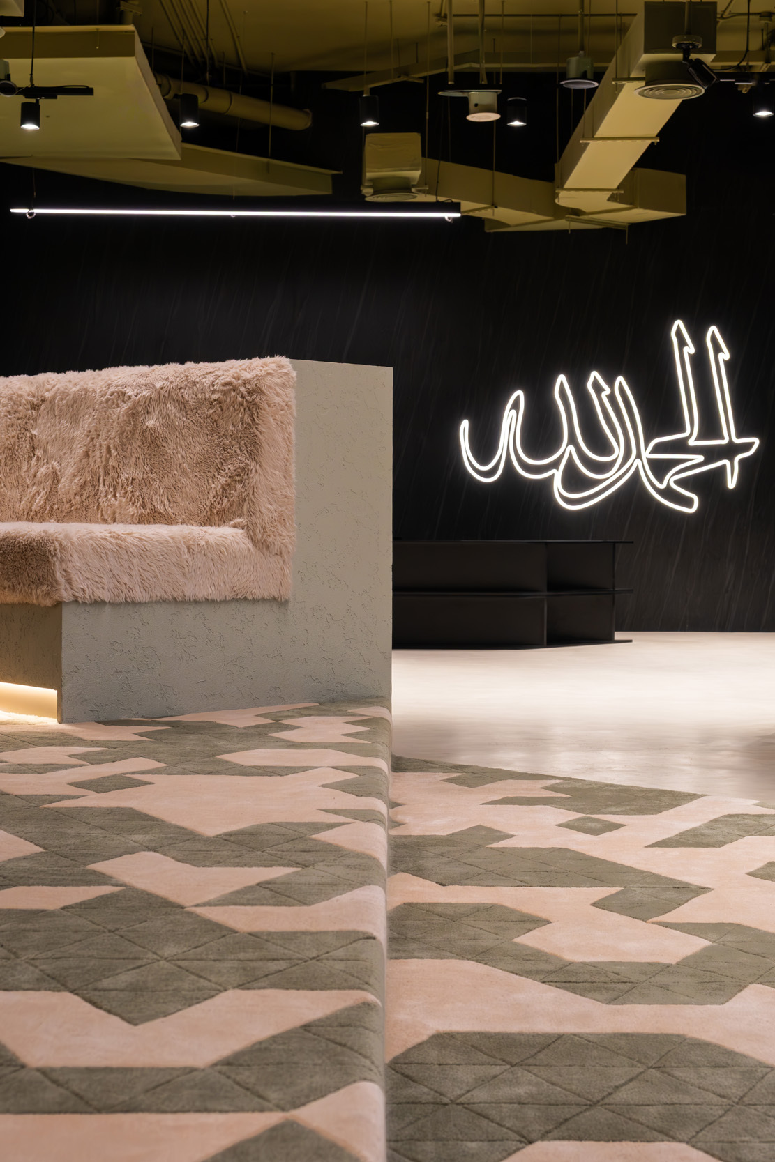 Corner of a textured pink reception counter against the black wall with illuminated calligraphic signage