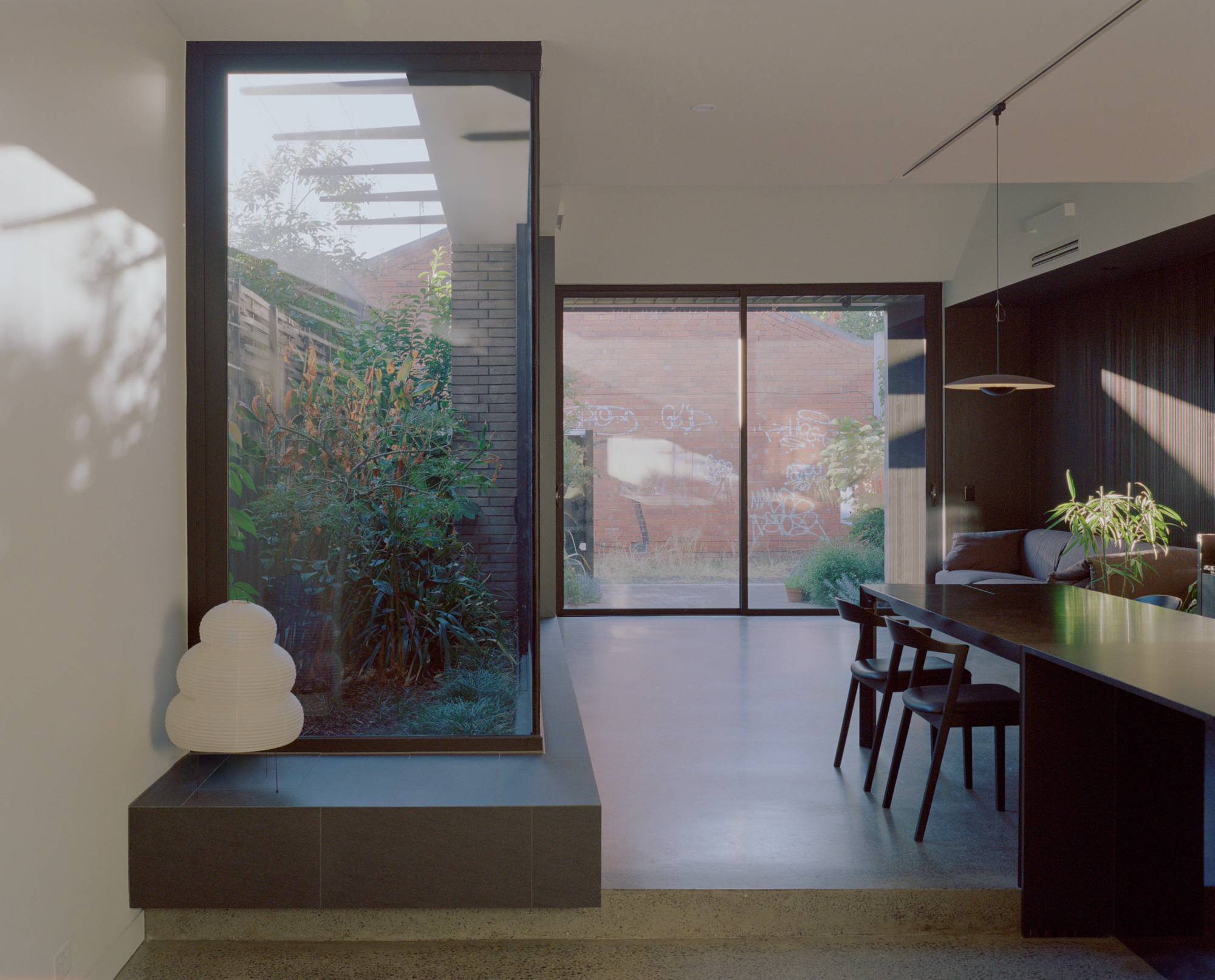 Open-plan dining area with glazed doors opening to planted courtyards on both sides