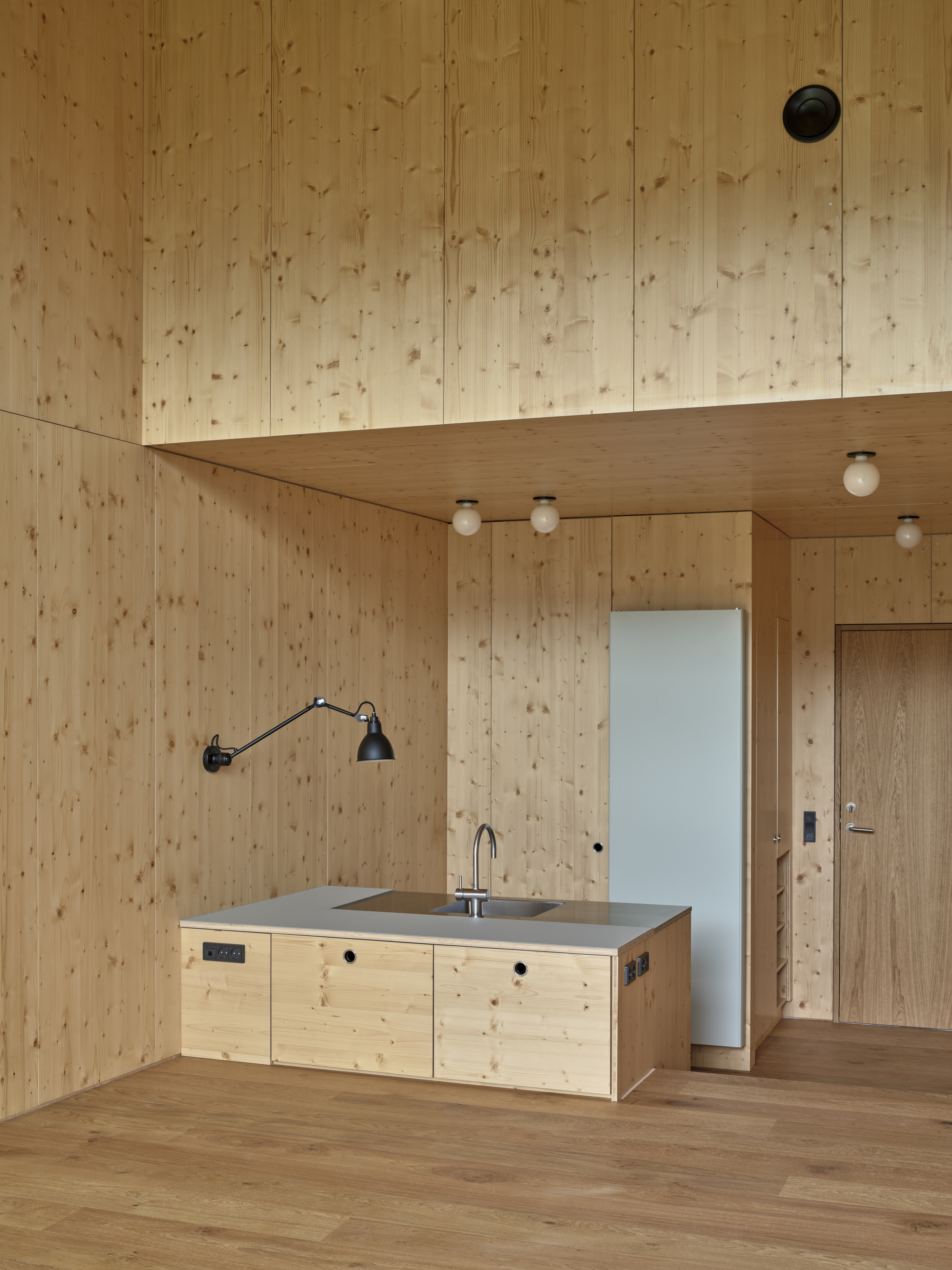 Plywood-lined room with freestanding kitchen island beneath a lowered ceiling plane and globe light fixtures