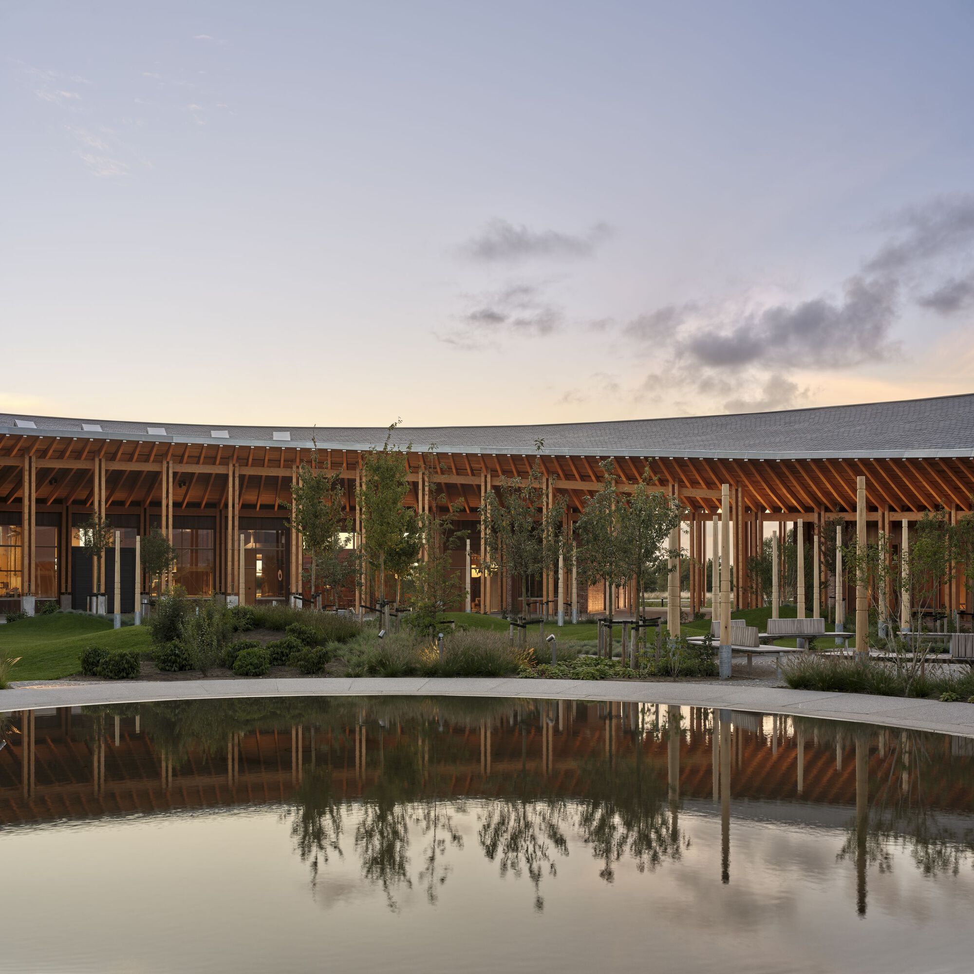 Timber-framed facade with central courtyard and reflecting pool at dusk