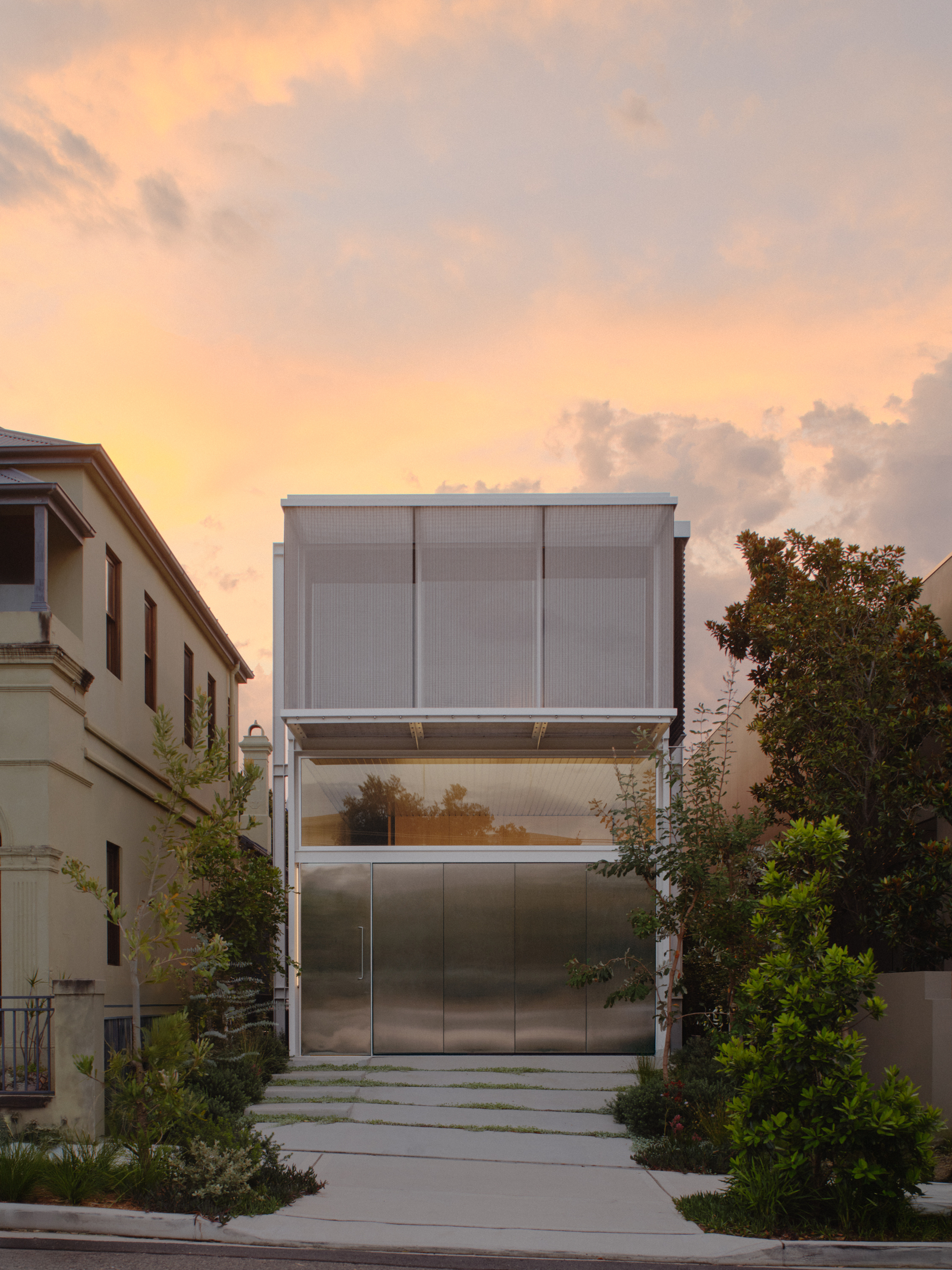 Street view of stacked metal and glass facade with translucent panels at sunset