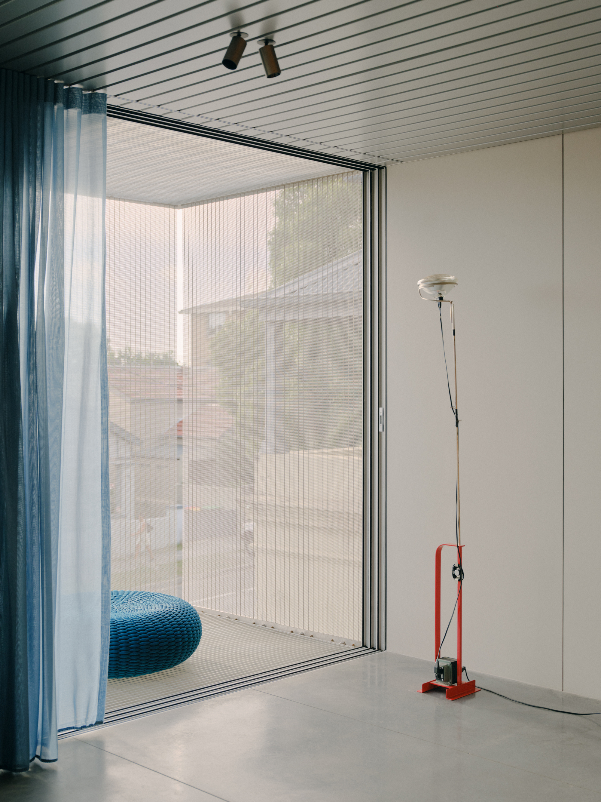 Sliding glass door with mesh screen and blue curtain opening to exterior terrace