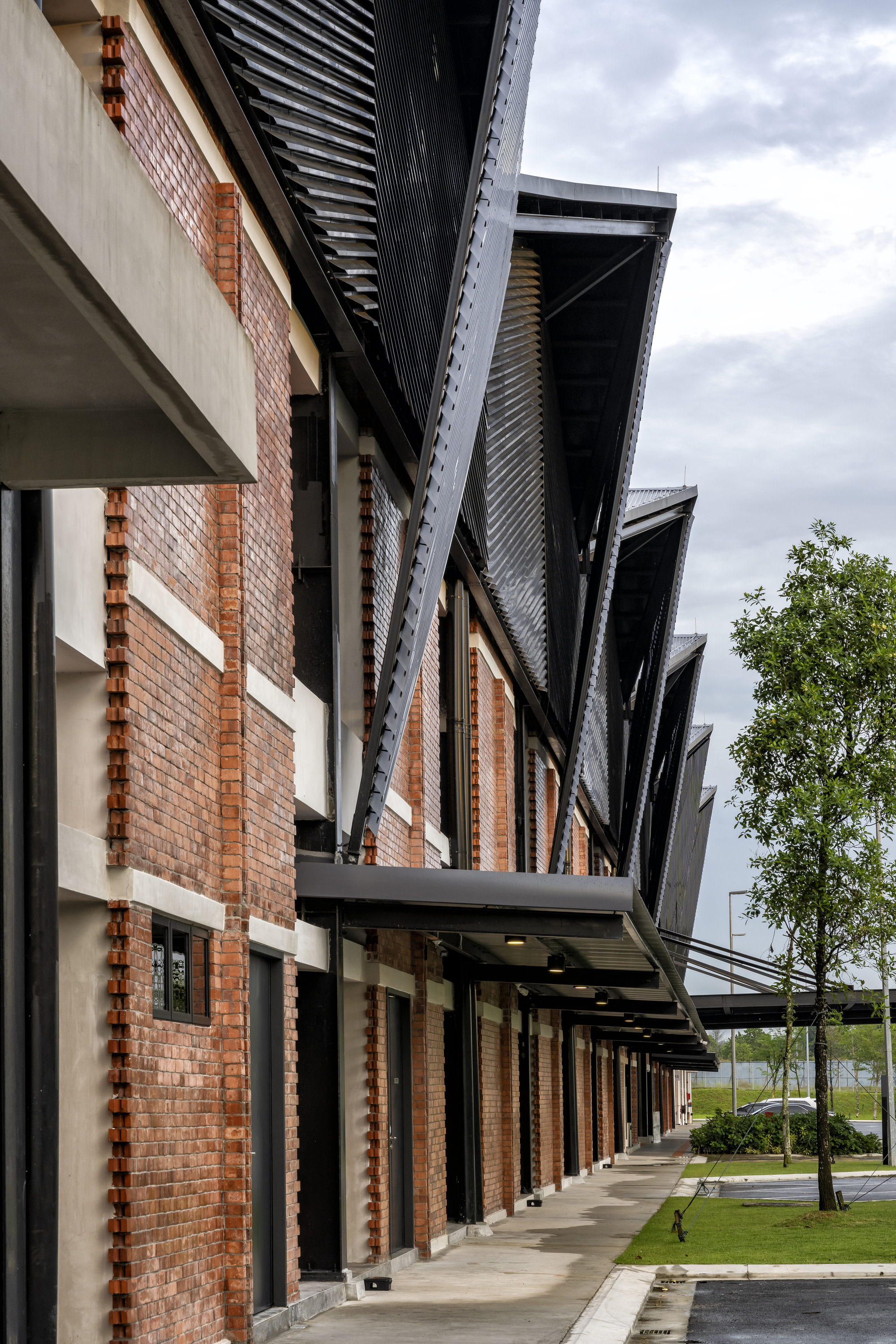 Covered walkway with brick facade and corrugated metal roof eaves under cloudy skies