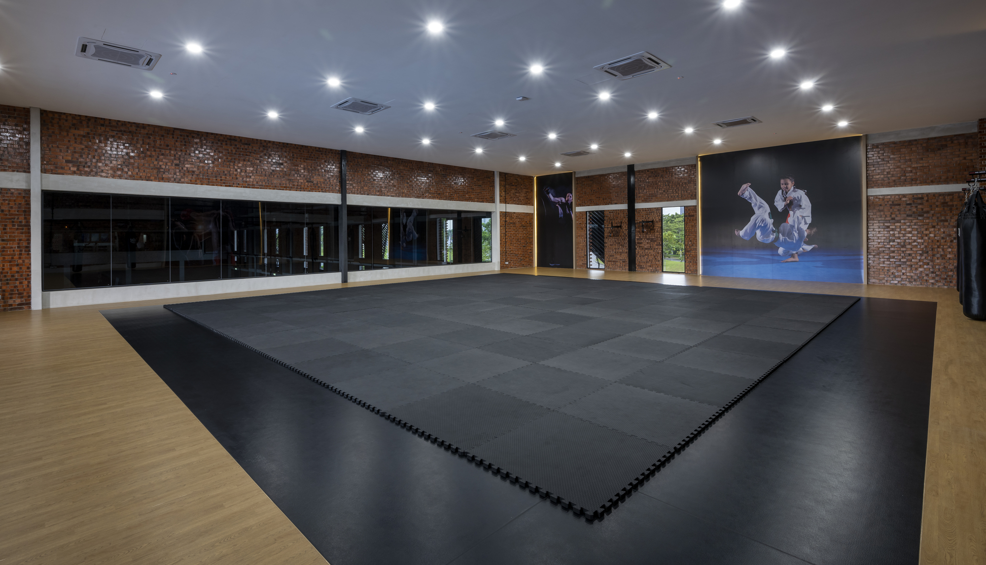 Interior training hall with black mat flooring and perforated brick walls under recessed ceiling lights