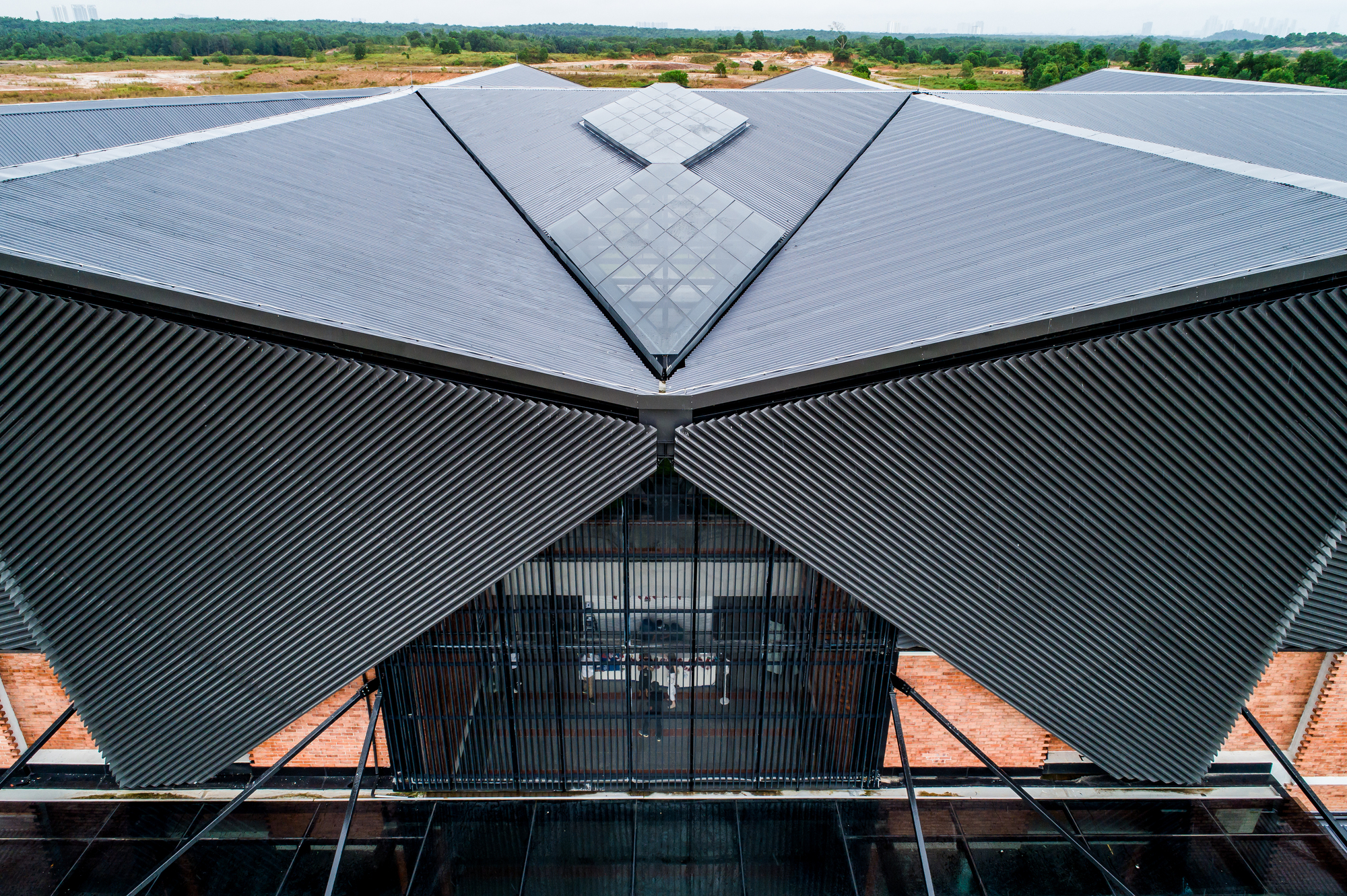 Aerial view of the triangular corrugated metal roof and central glazed gable in open landscape