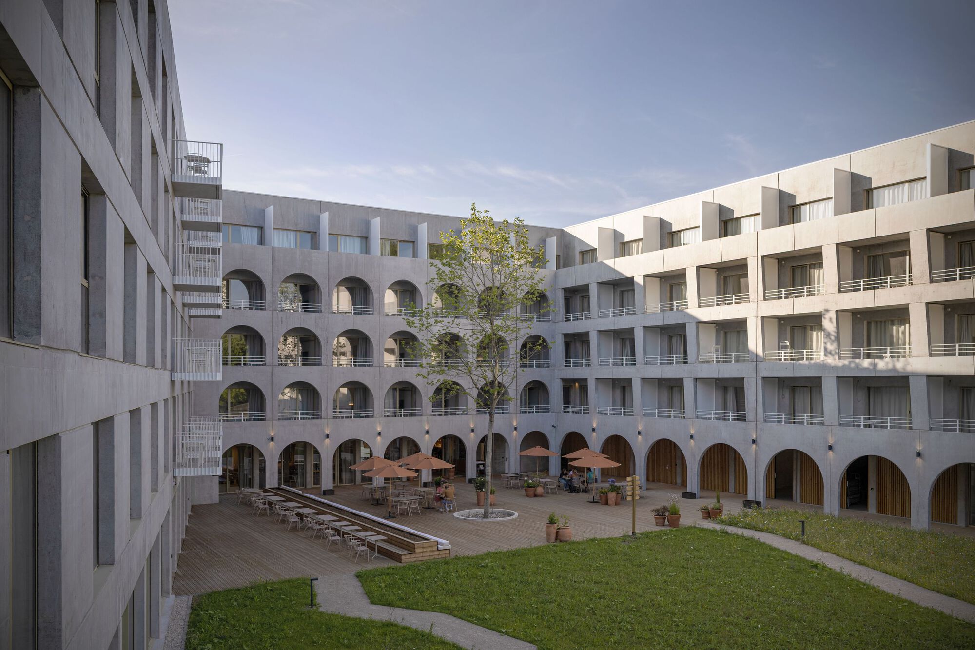 Interior courtyard with arched colonnade surrounding a grassed lawn and scattered outdoor seating