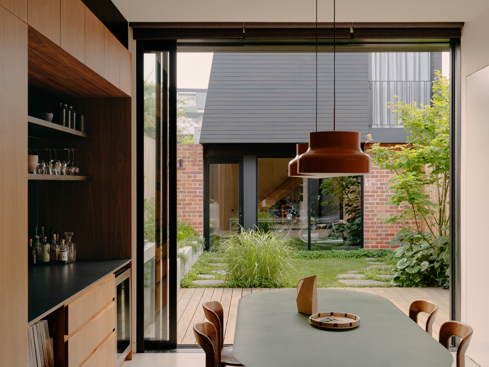 Interior dining area looking through glazed doors to a small planted courtyard