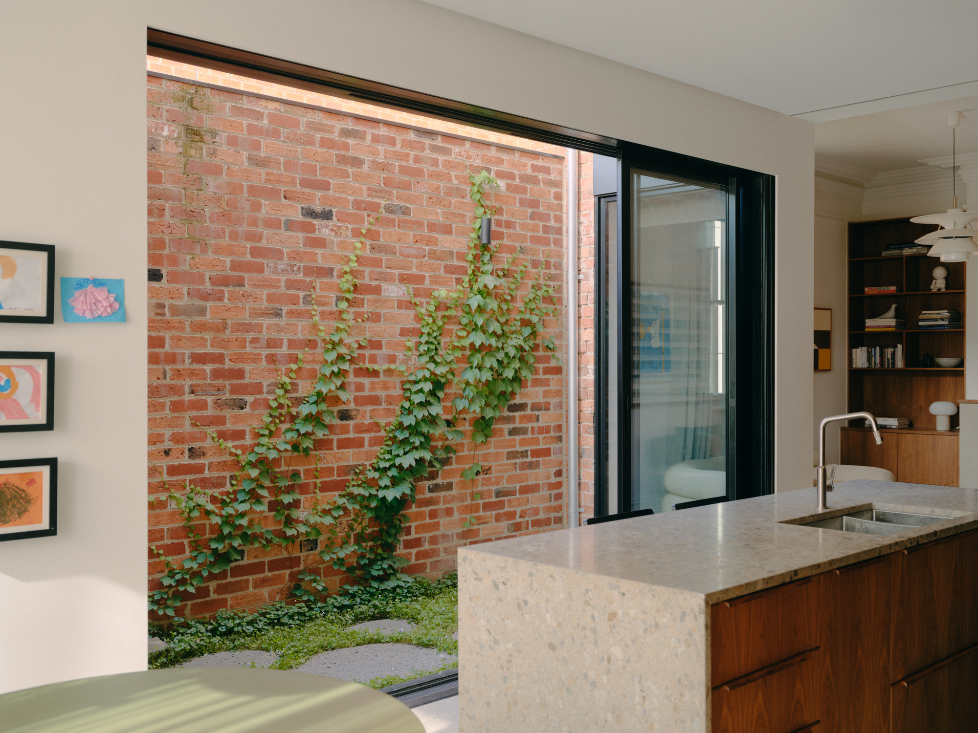 Kitchen island with terrazzo countertop overlooking a small brick-walled courtyard with climbing vines