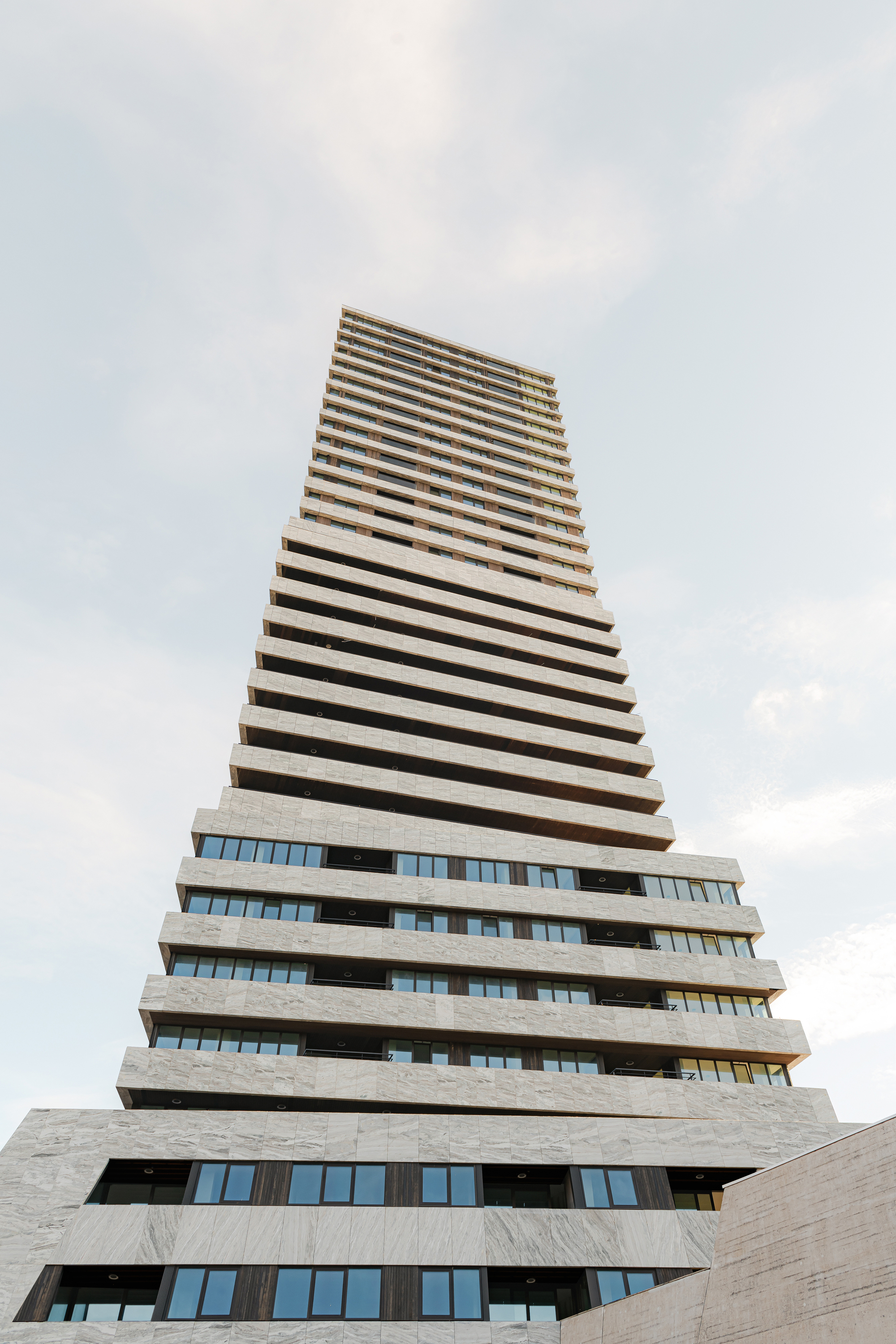 Upward view of the stepped concrete balconies forming a tapering tower against cloudy skies