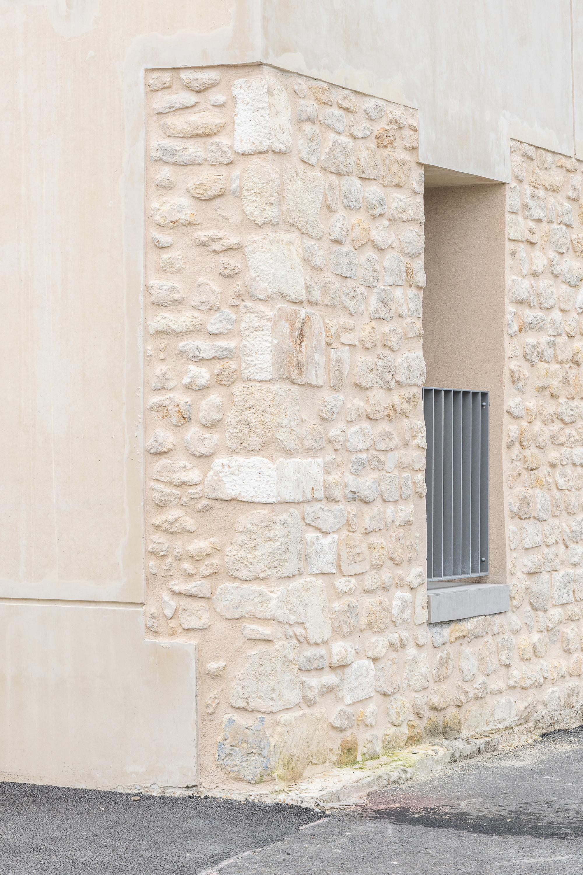 Close-up of the limestone wall corner with a small recessed window and smooth plaster edge