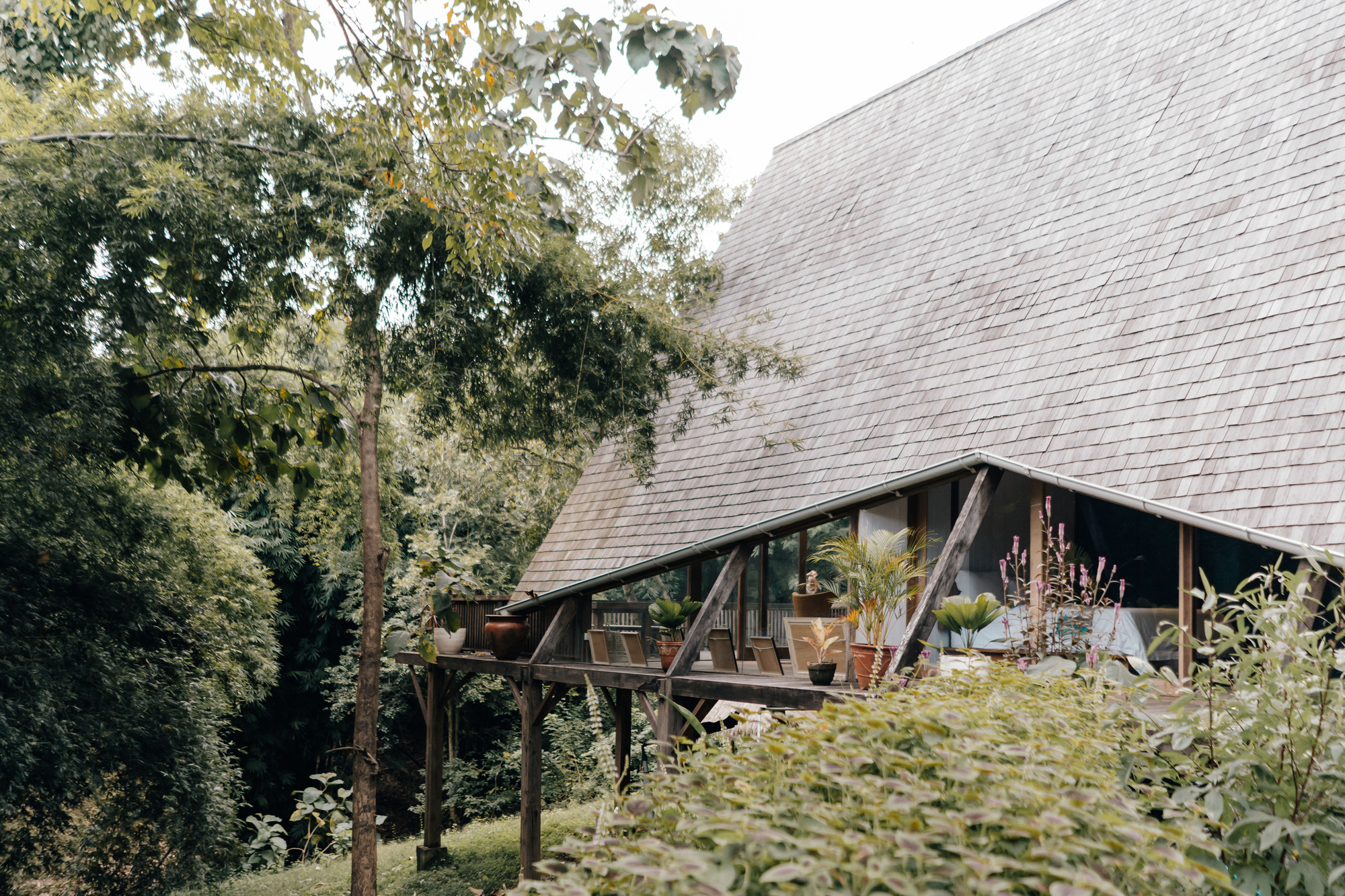 Covered terrace with exposed timber posts and potted plants beneath the sloped tile roof