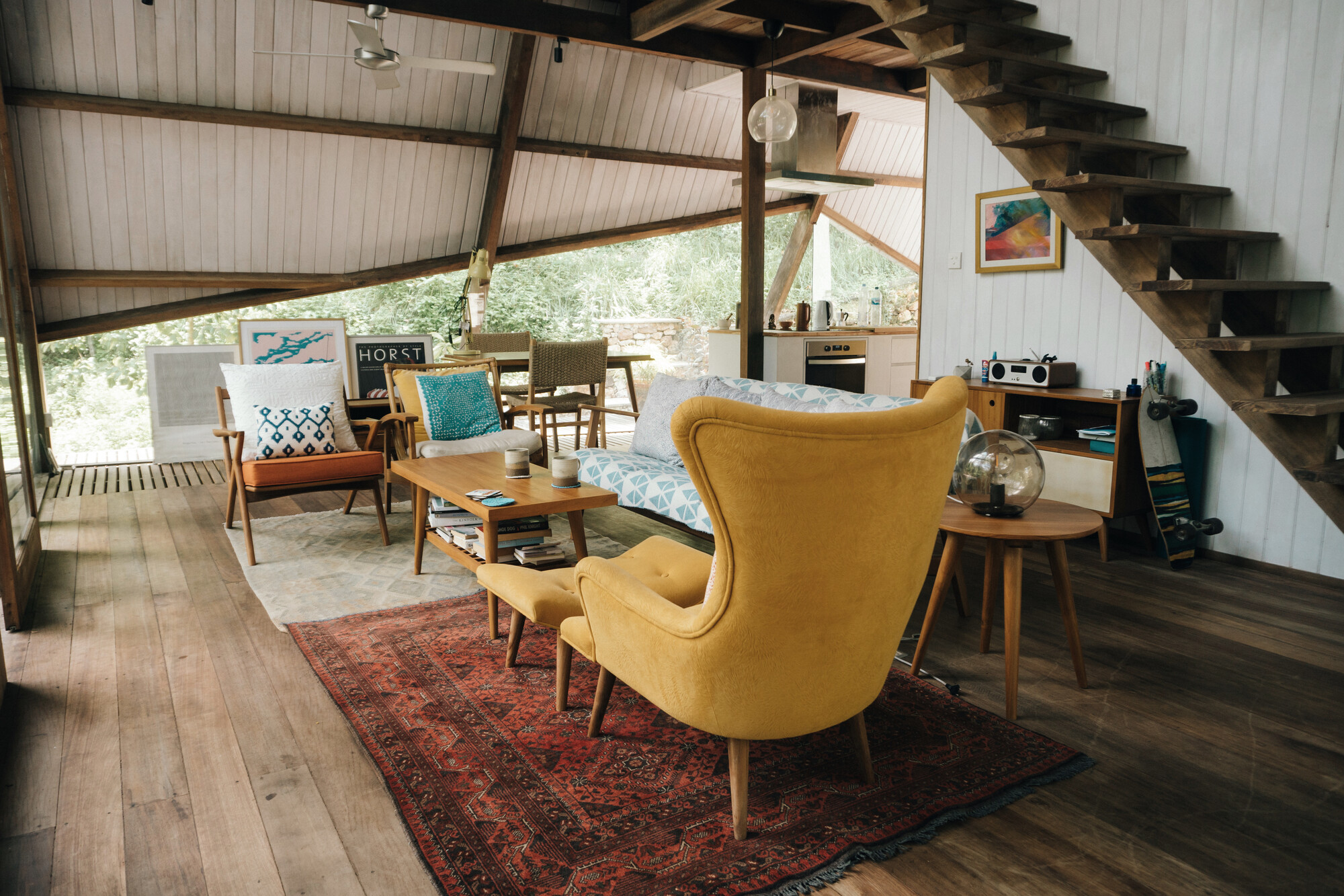 Living area with timber flooring, patterned rug and open stair beneath diagonal bracing