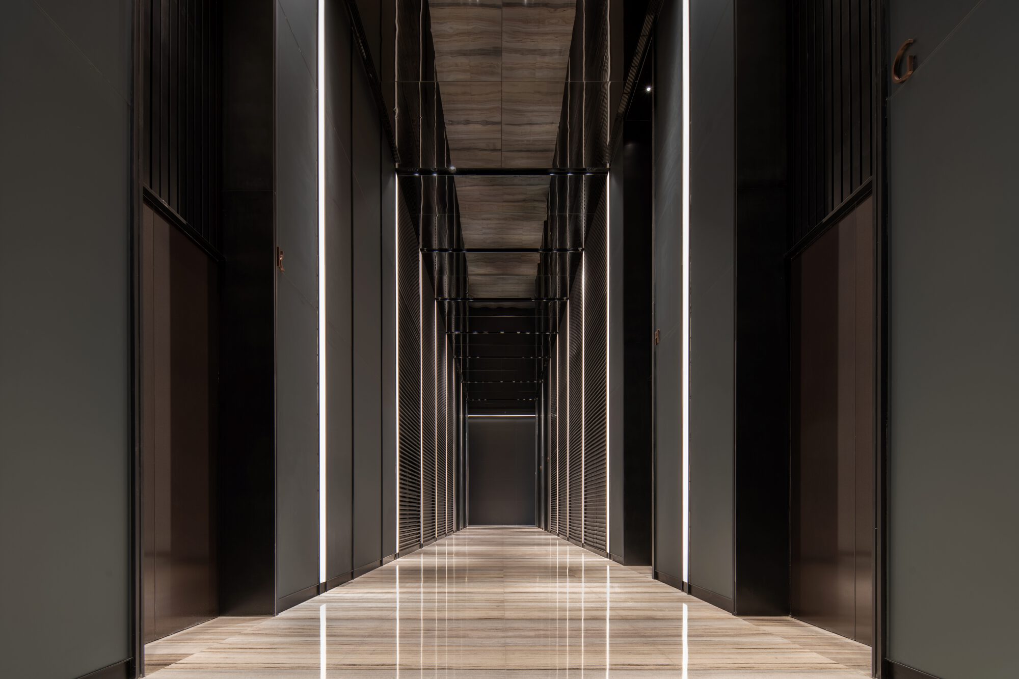 Long hallway with dark metal panels, vertical cable detailing and linear ceiling lights reflecting on polished floor