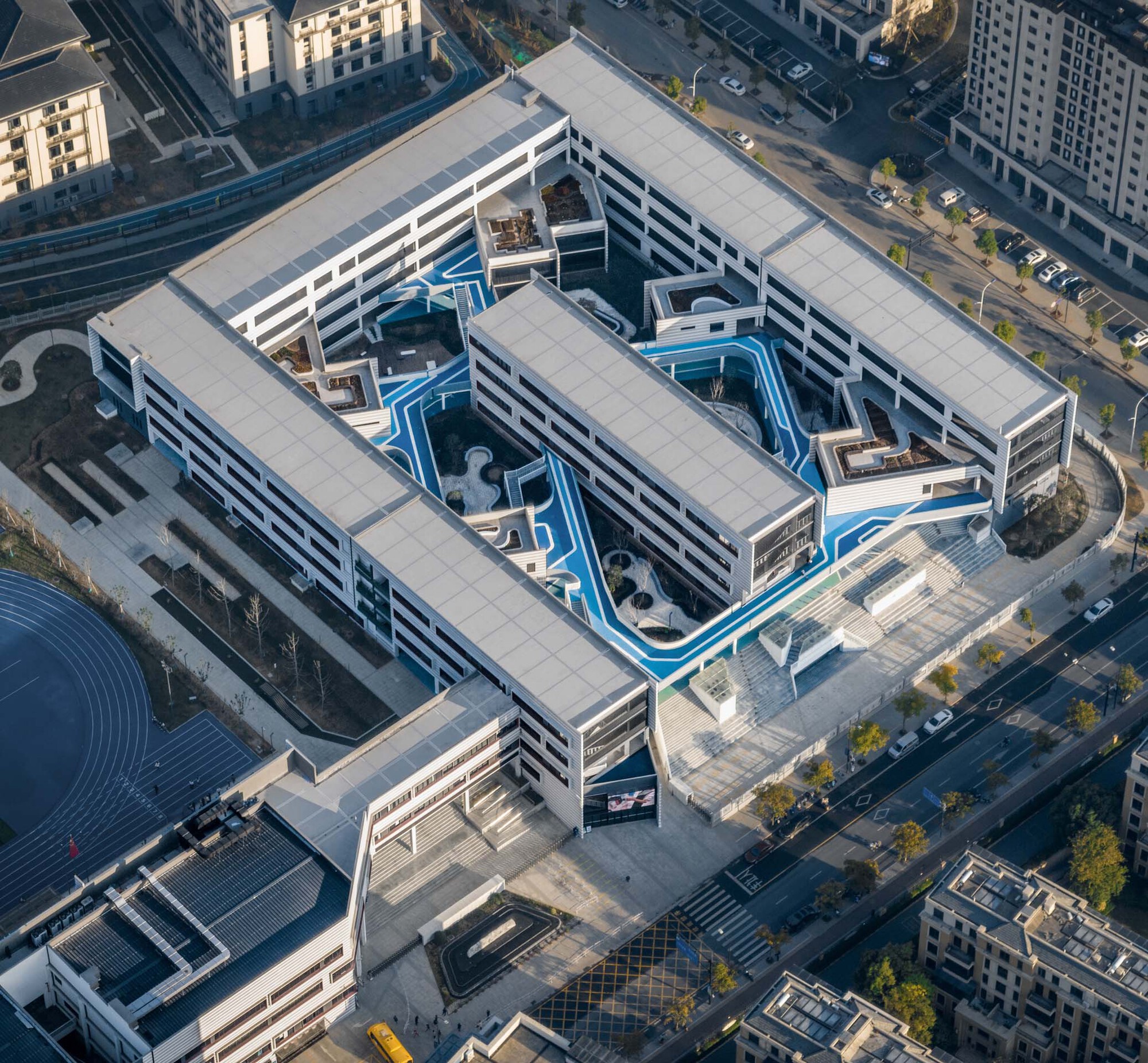 Aerial view of perimeter block building with blue interior courtyard pathways in morning light