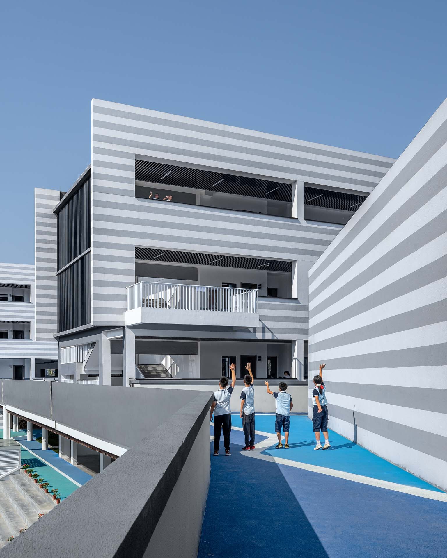 Rooftop playground with blue safety surfacing and students gathering under clear blue sky