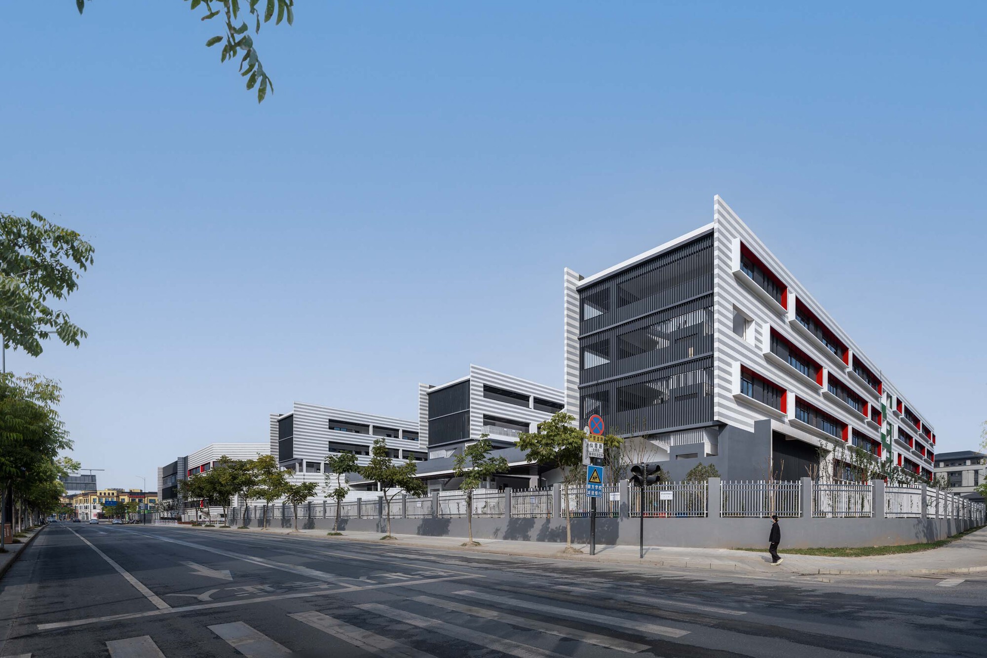 Corner view from the street showing layered white and dark grey facade with pedestrian passing by