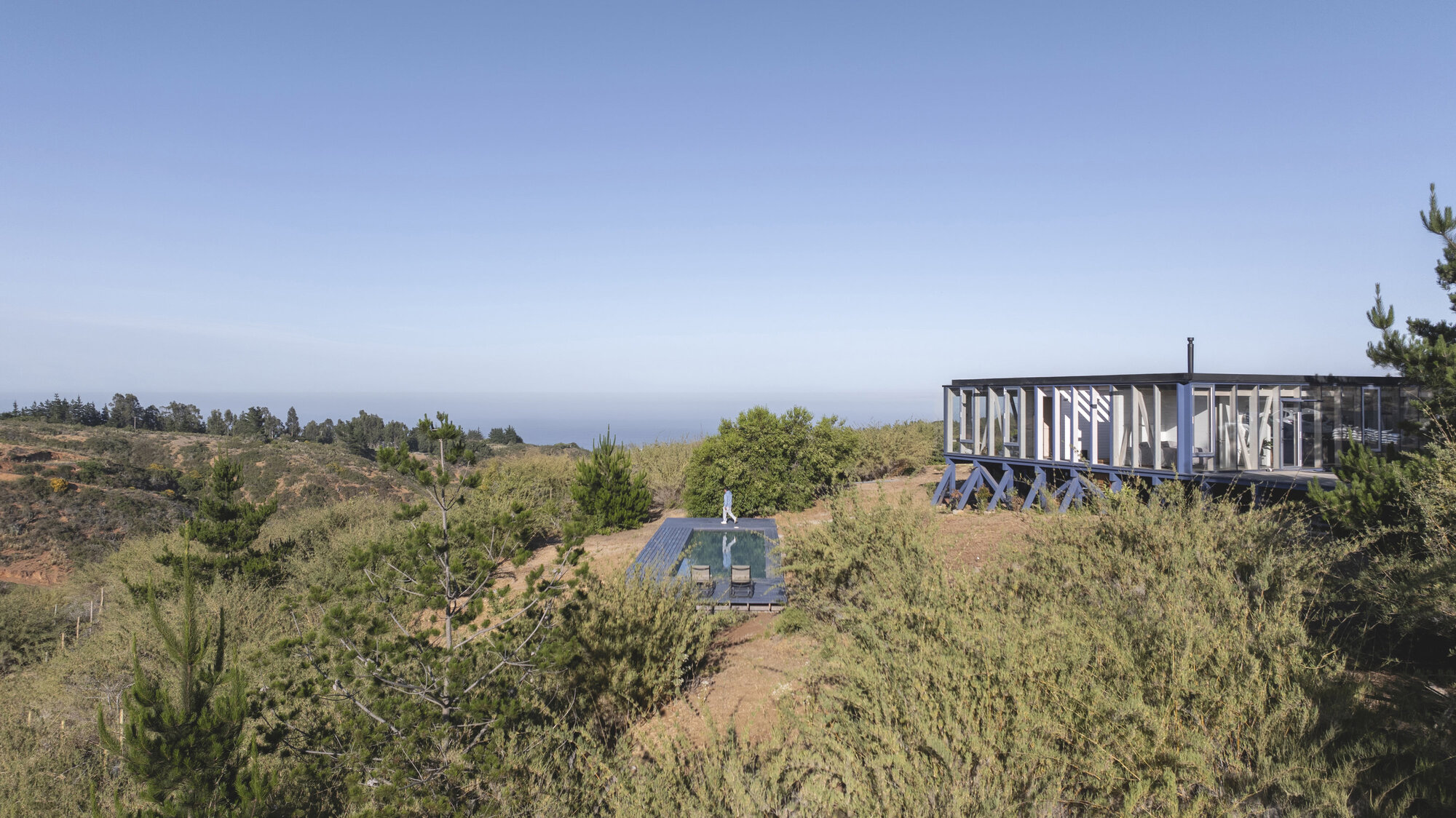 Elevated structure and small outbuilding set among scrubland with ocean on the horizon