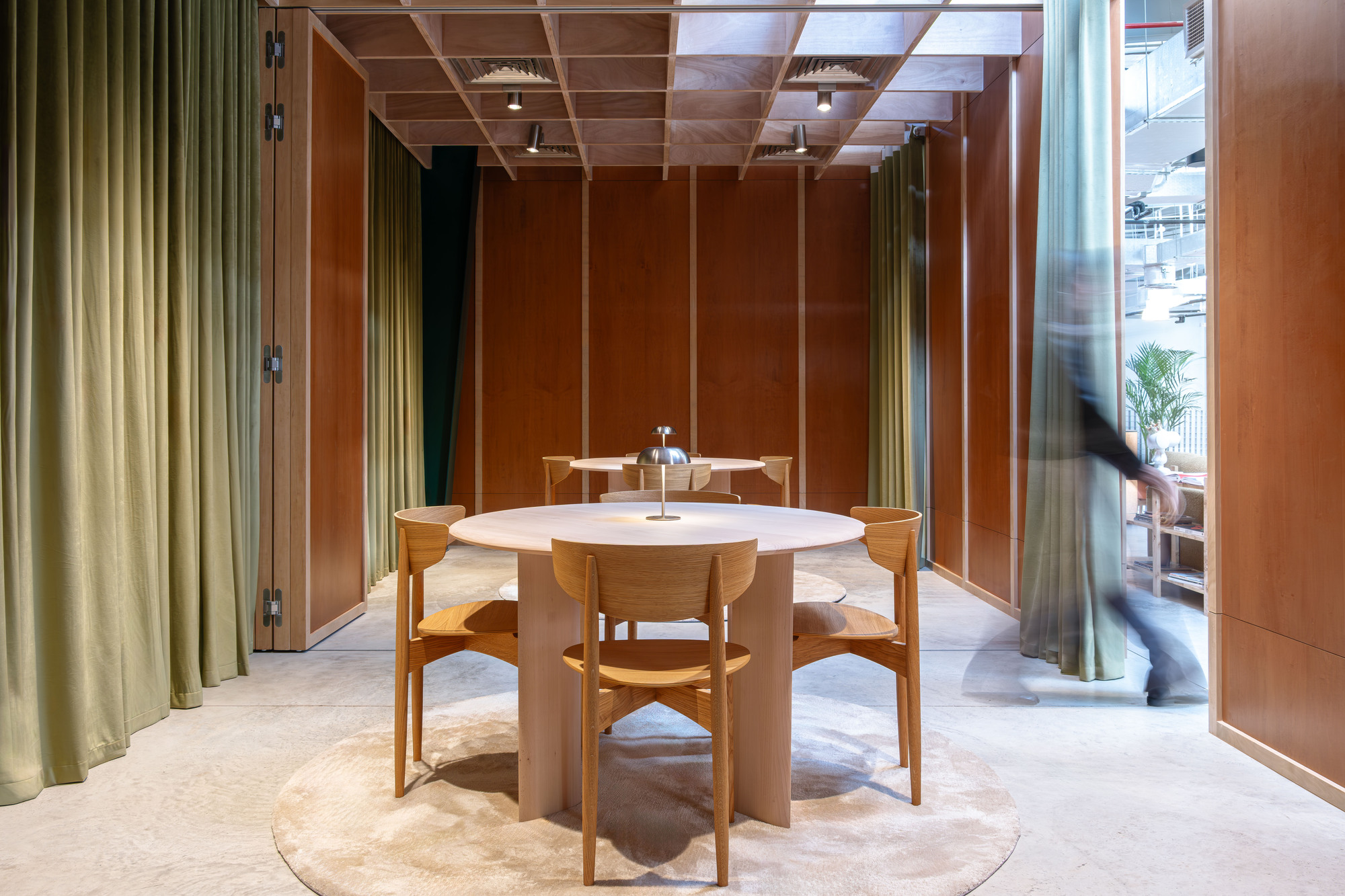 Private dining room with timber coffered ceiling and olive drapery framing a passing figure