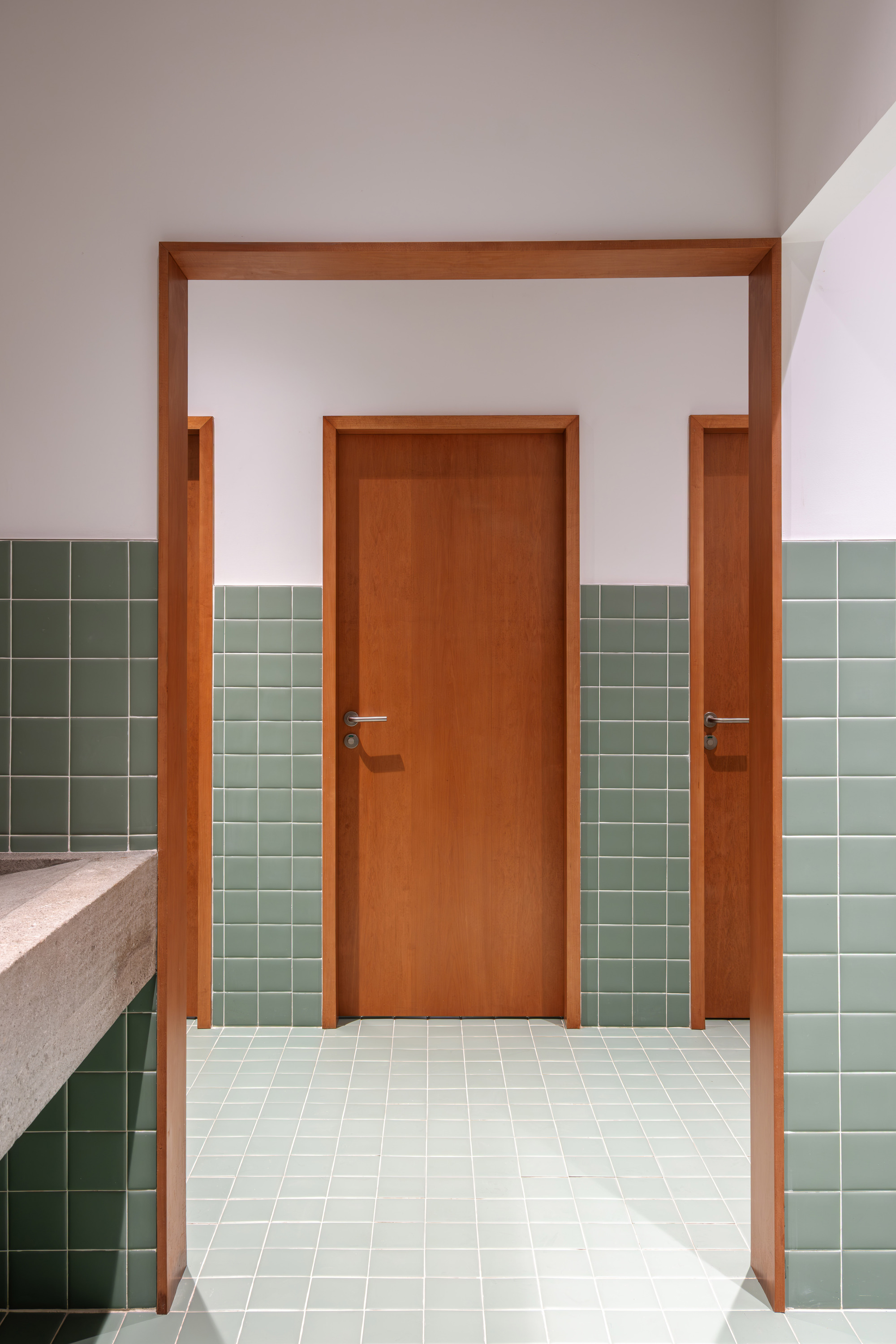 Hallway with timber door framed by sage green tile wainscoting and cream terrazzo countertop