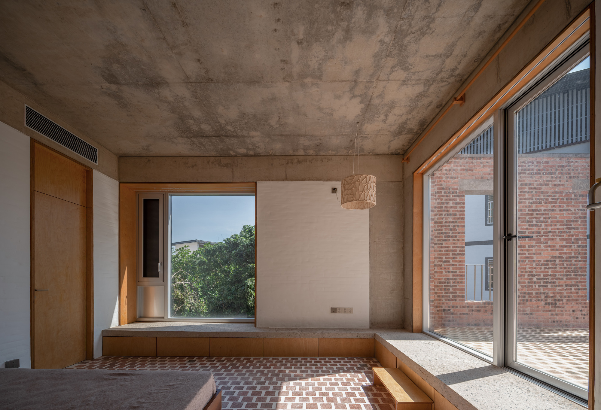 Built-in timber window seat with view to courtyard and exposed concrete soffit casting geometric shadows