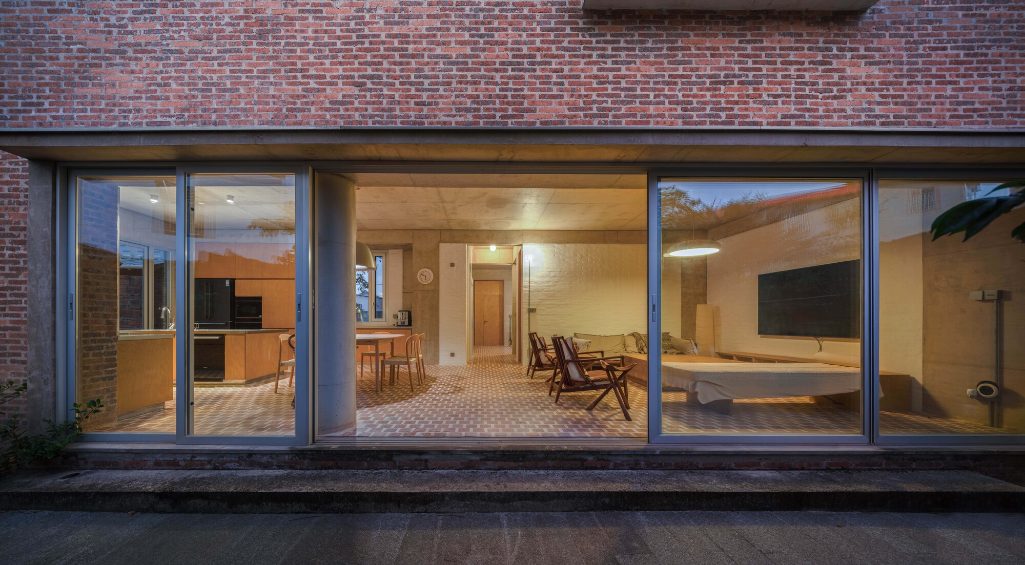 Glazed rear facade opening to interior living spaces illuminated at dusk