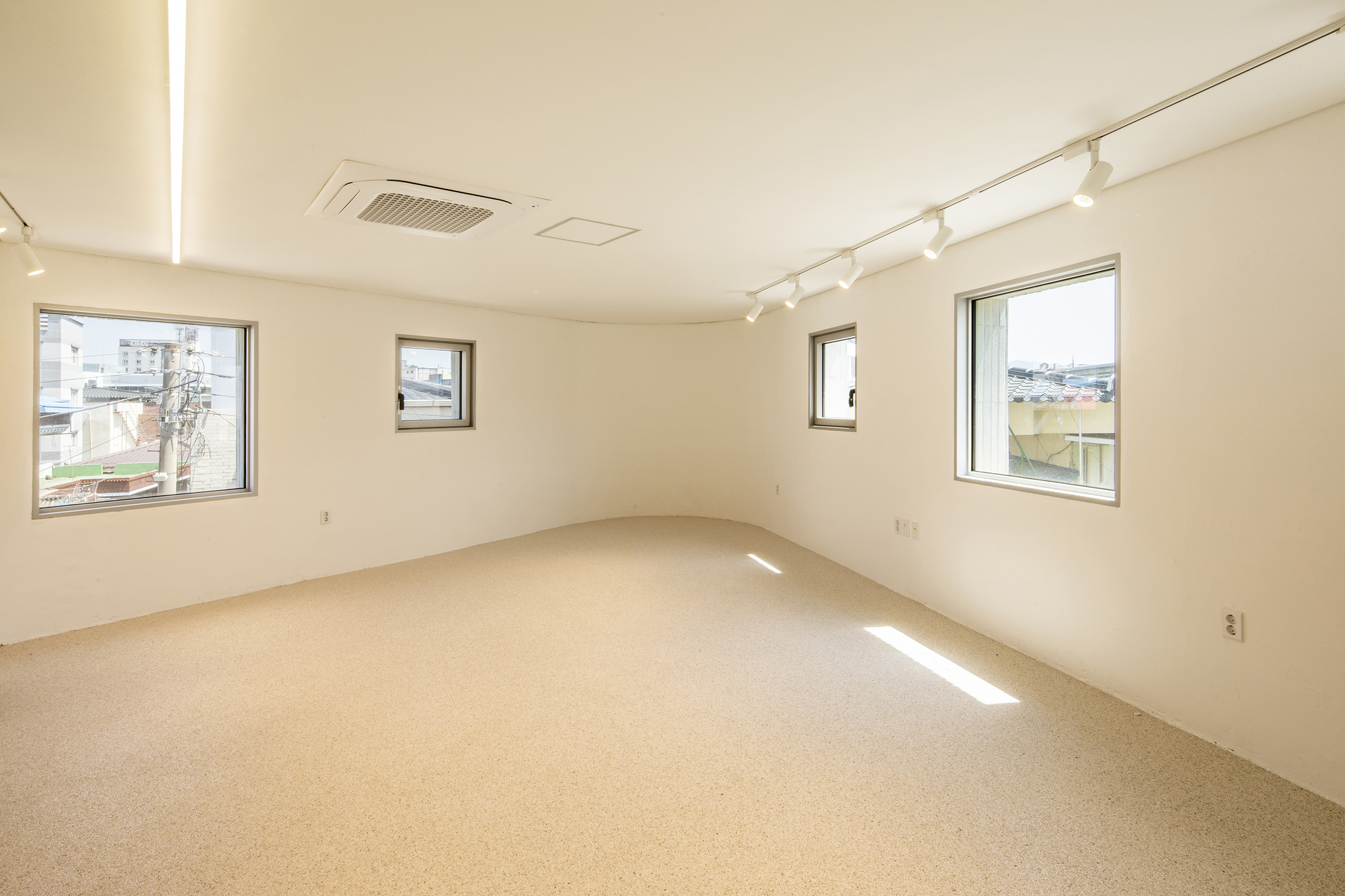 Interior room with terrazzo flooring and three square windows framing views of the surrounding neighborhood