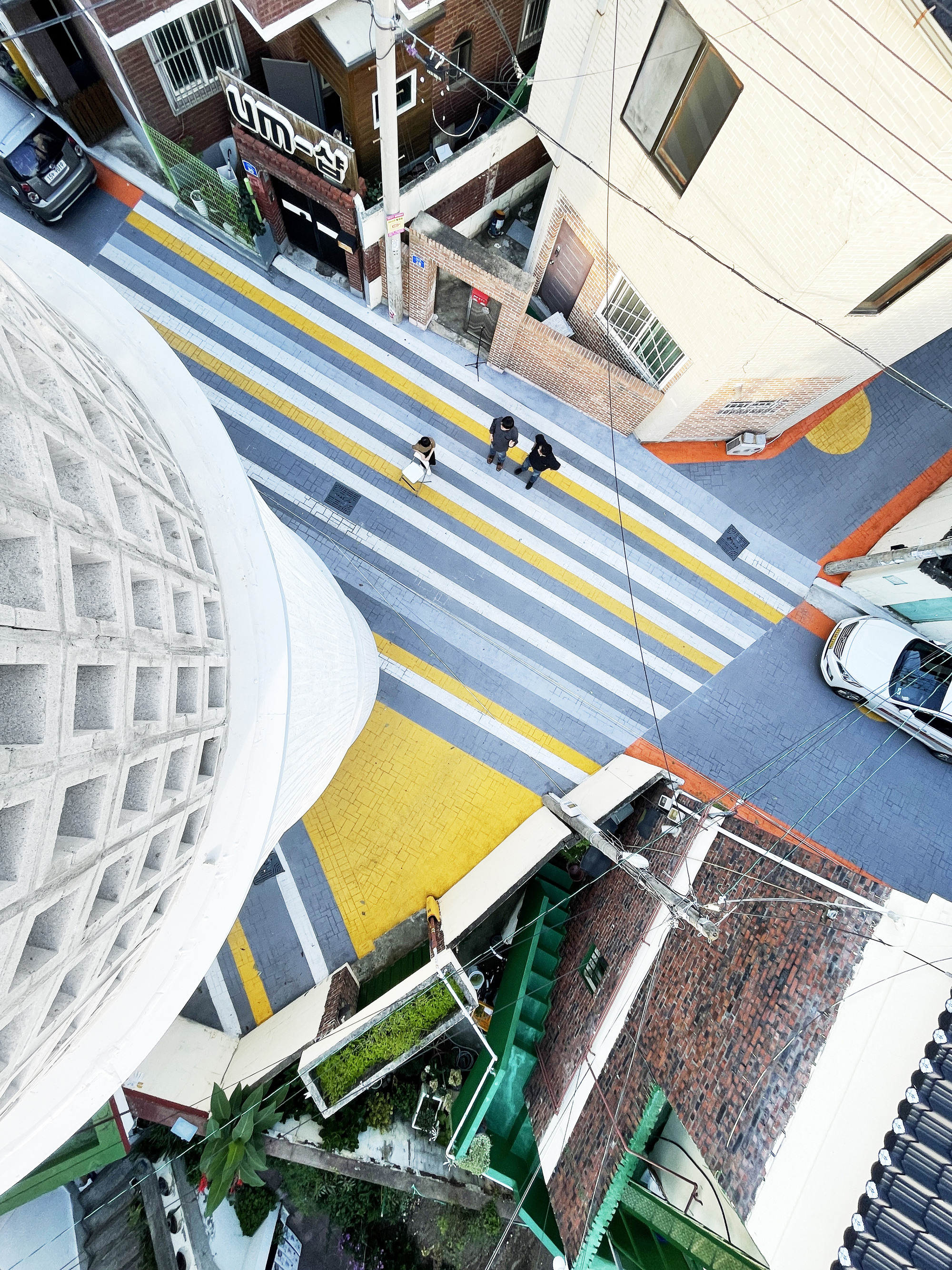 Aerial view looking down the curved facade onto the striped crosswalk with pedestrians below