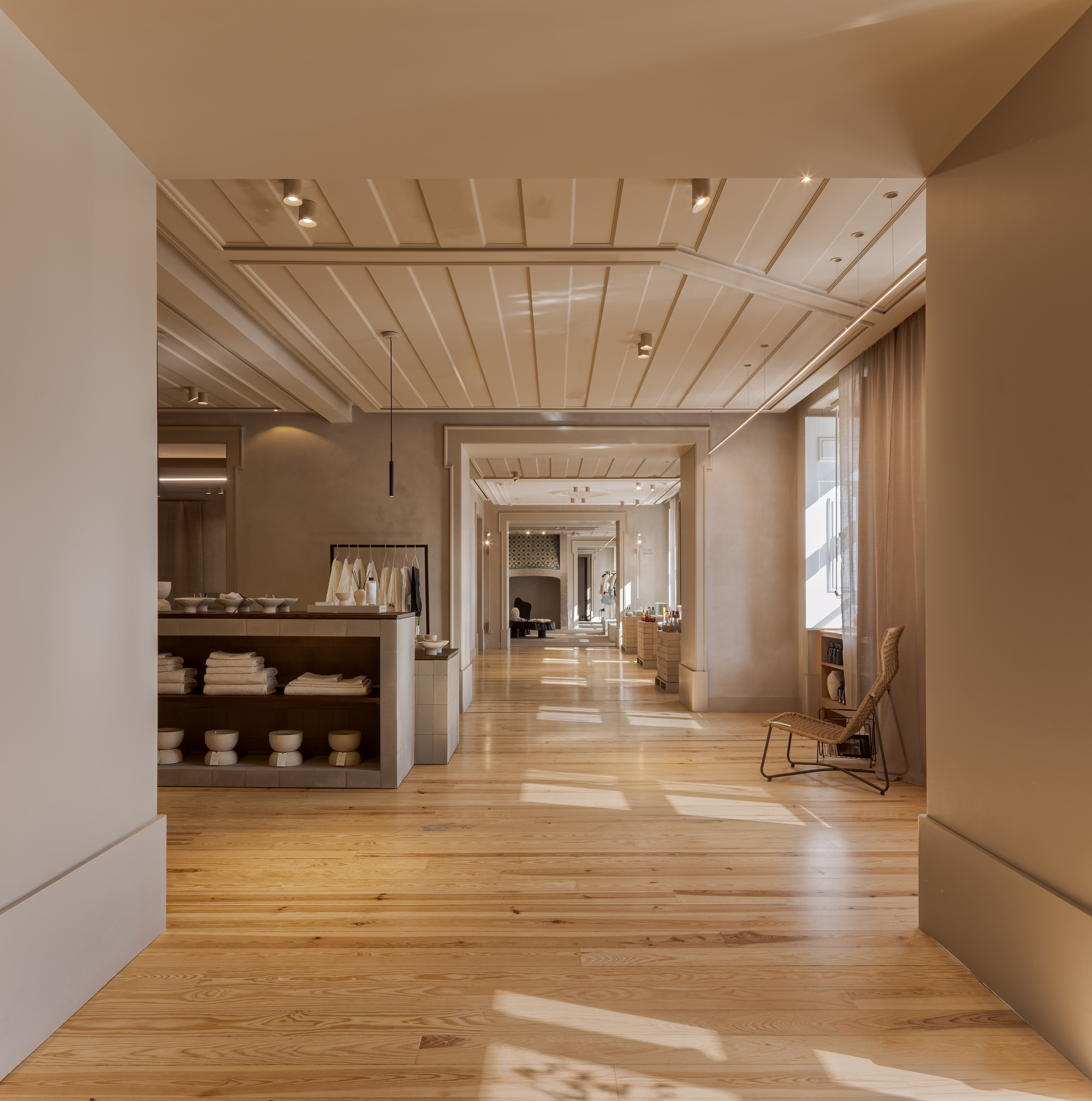 Long corridor with timber plank ceiling, oak flooring and sunlight patches leading through successive doorways