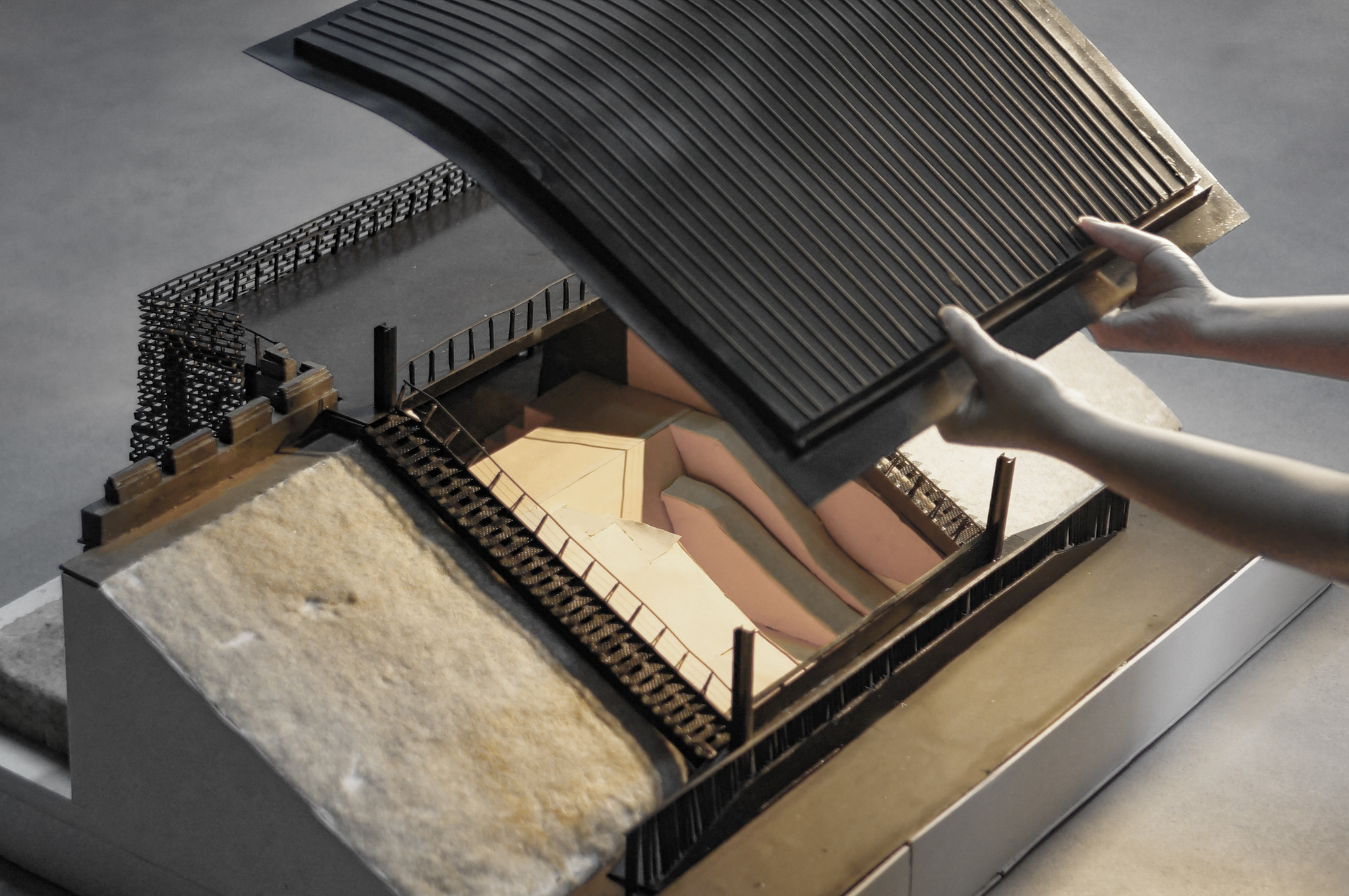 Cutaway model view showing interior courtyard spaces beneath a lifted ribbed roof section