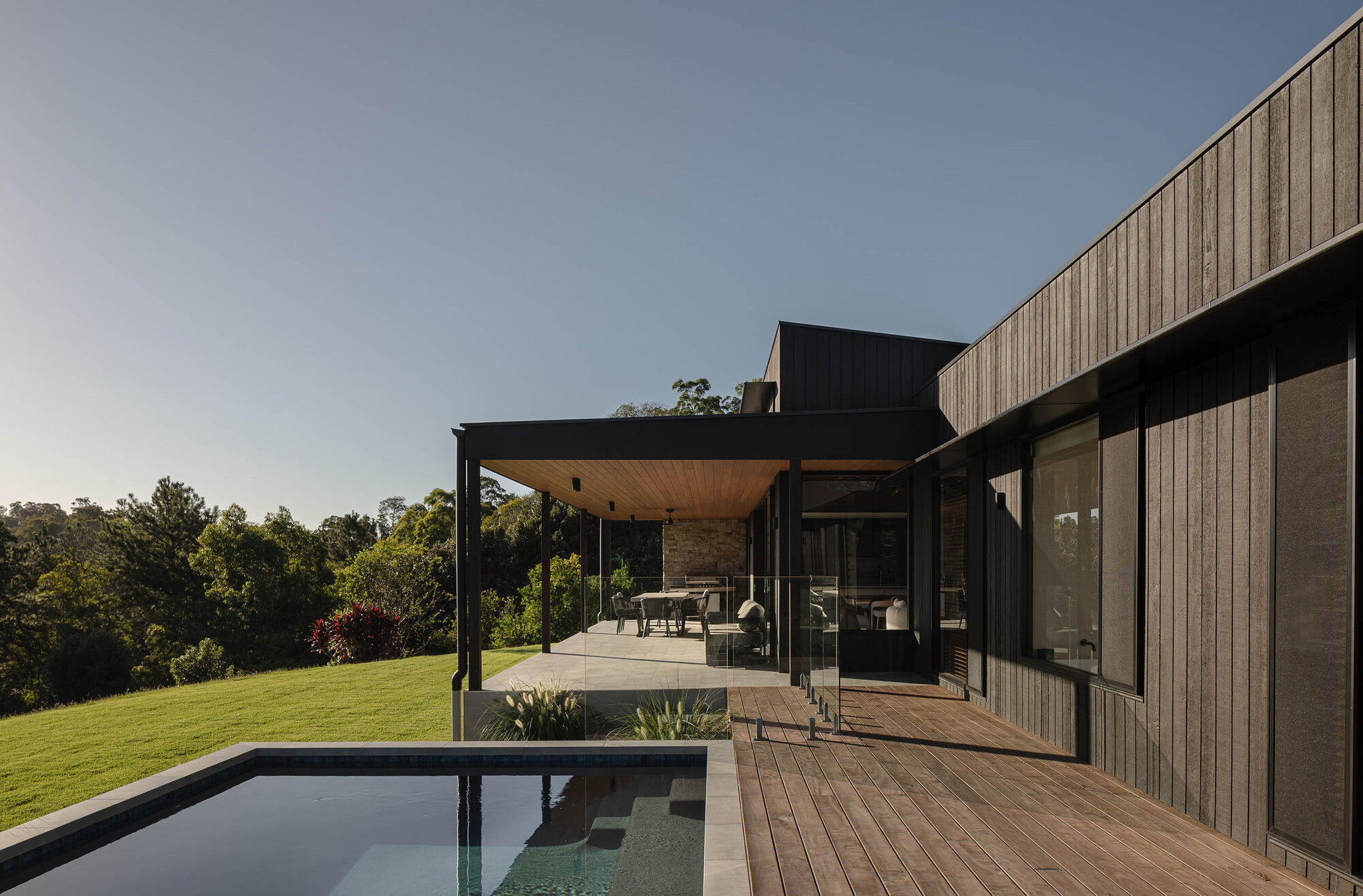 Rear terrace with timber deck and lap pool overlooking the landscape at dusk