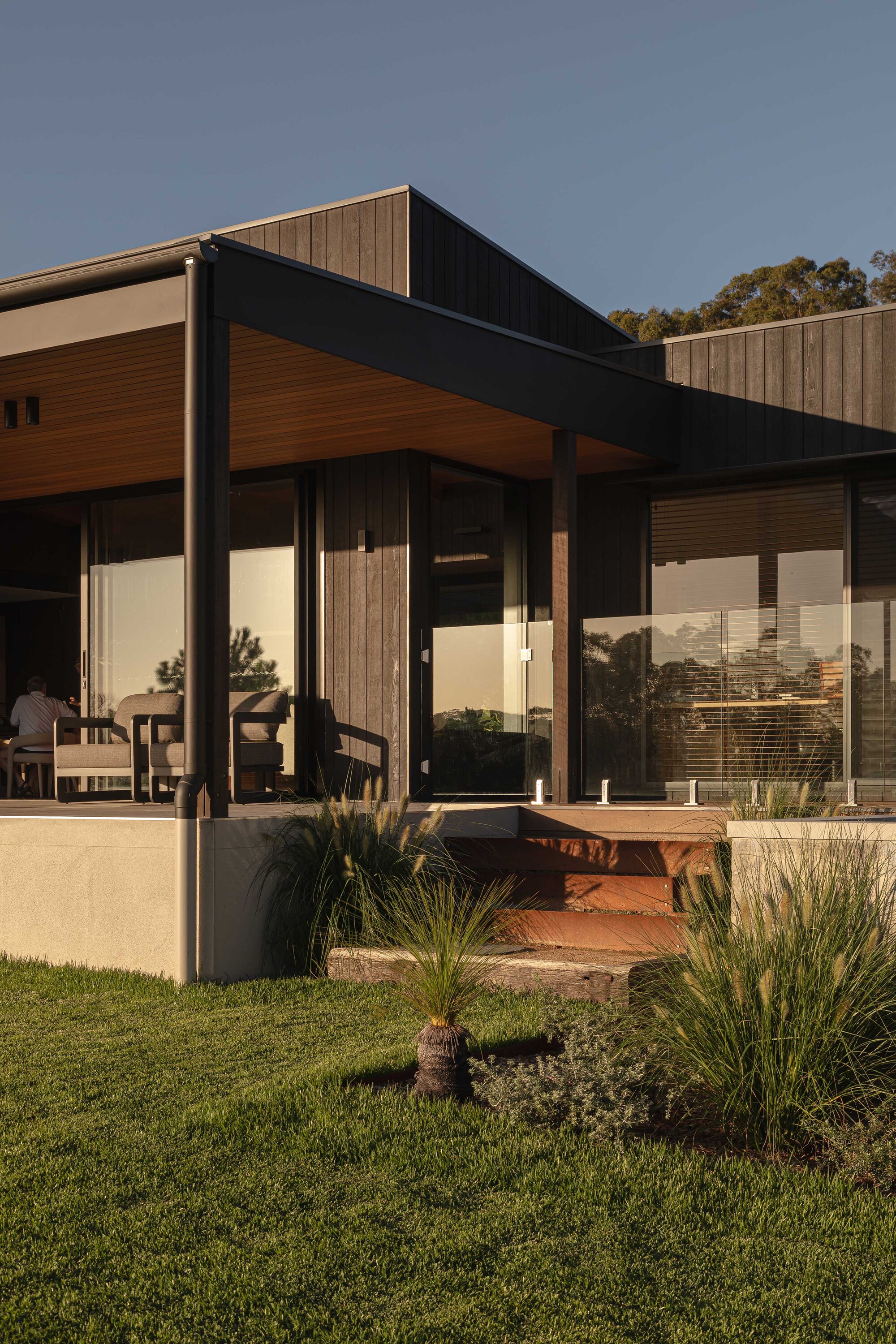 Entry courtyard with planted beds in red soil beneath the cantilevered roof soffit