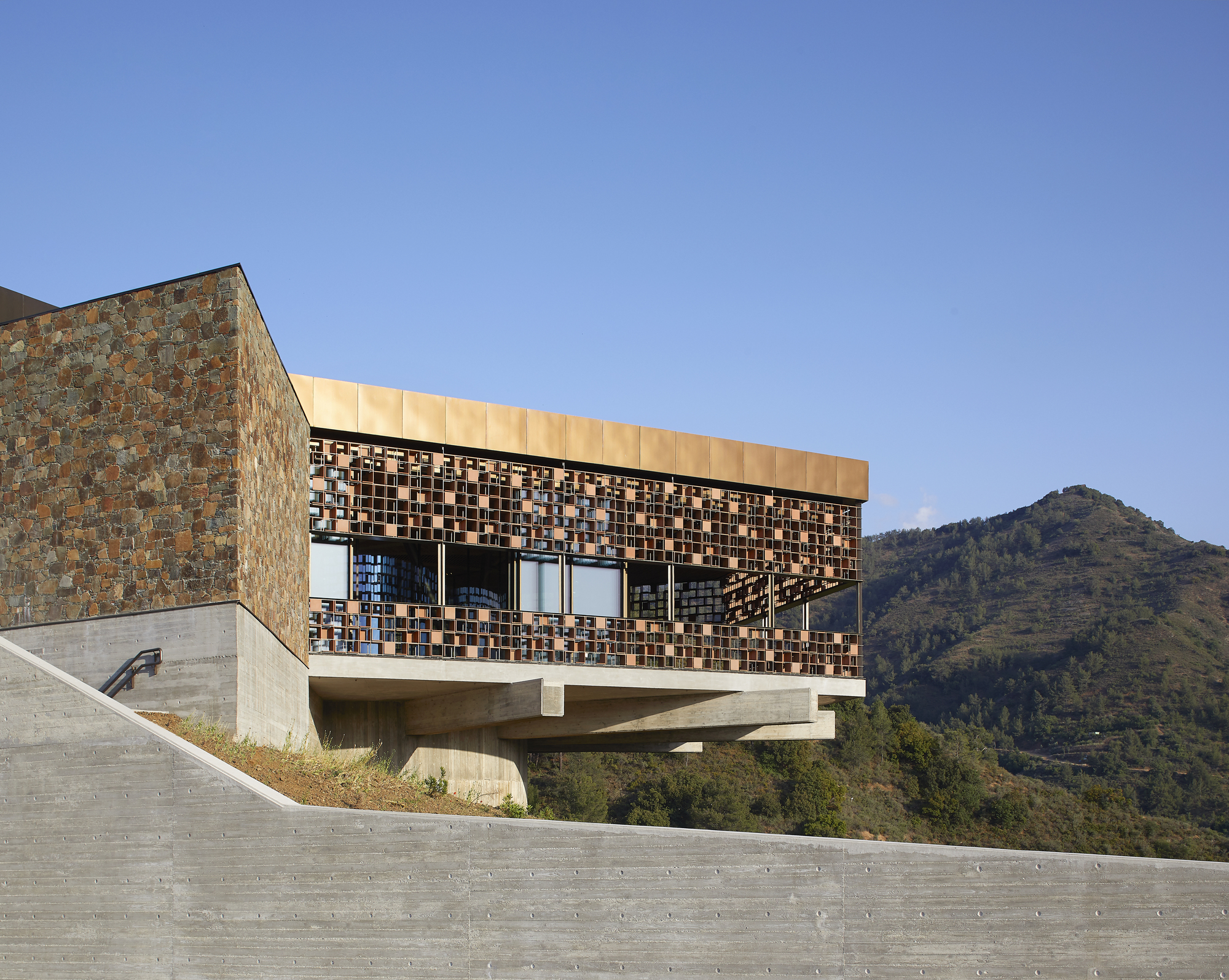 Upper volume with patterned tile screen and ribbon windows overlooking mountain terrain in daylight