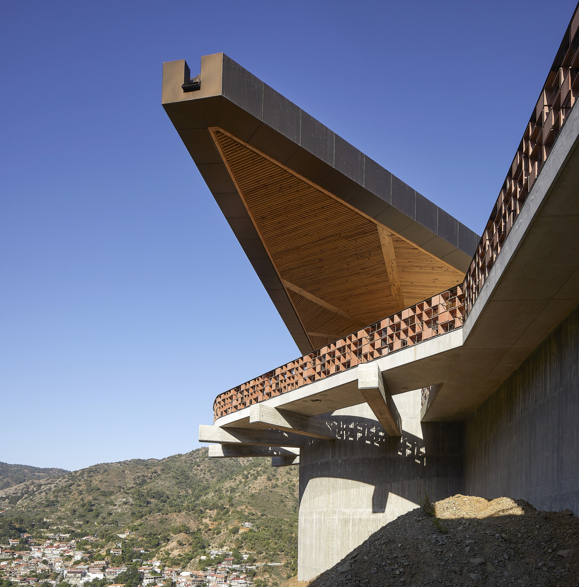 Underside view of the cantilevered roof with timber slat soffit and concrete support columns