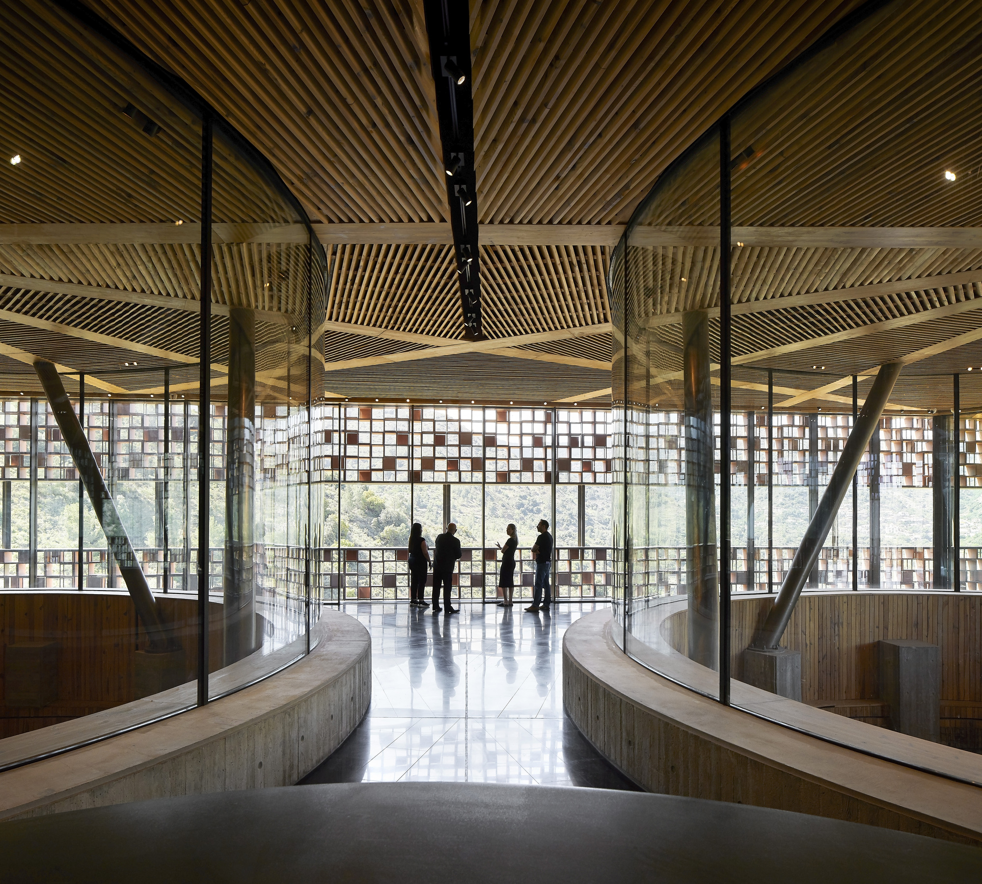 Central hall with ribbed timber ceiling, curved balconies and visitors silhouetted against perforated screens