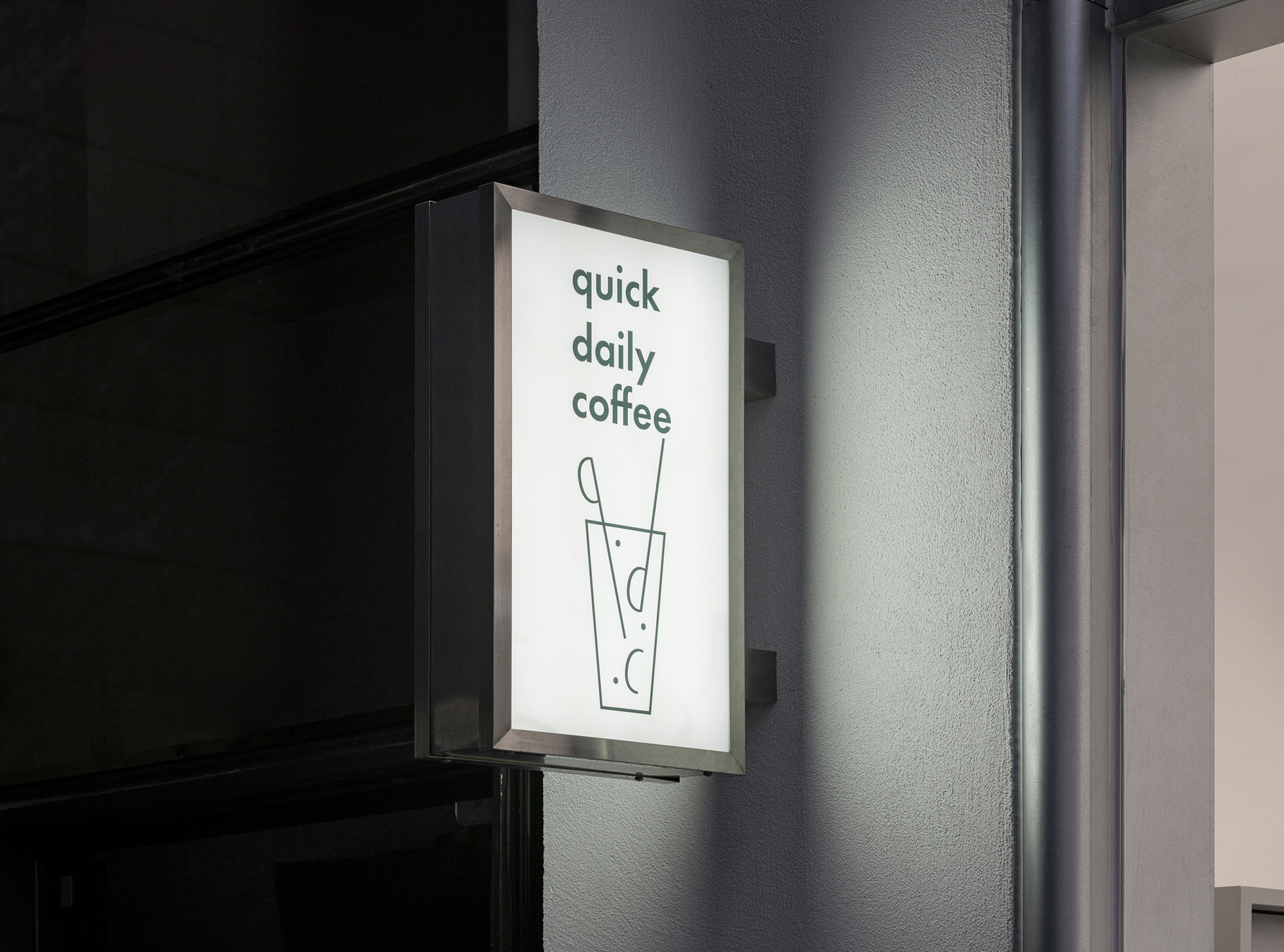 Backlit wall-mounted signage panel against a textured gray exterior wall