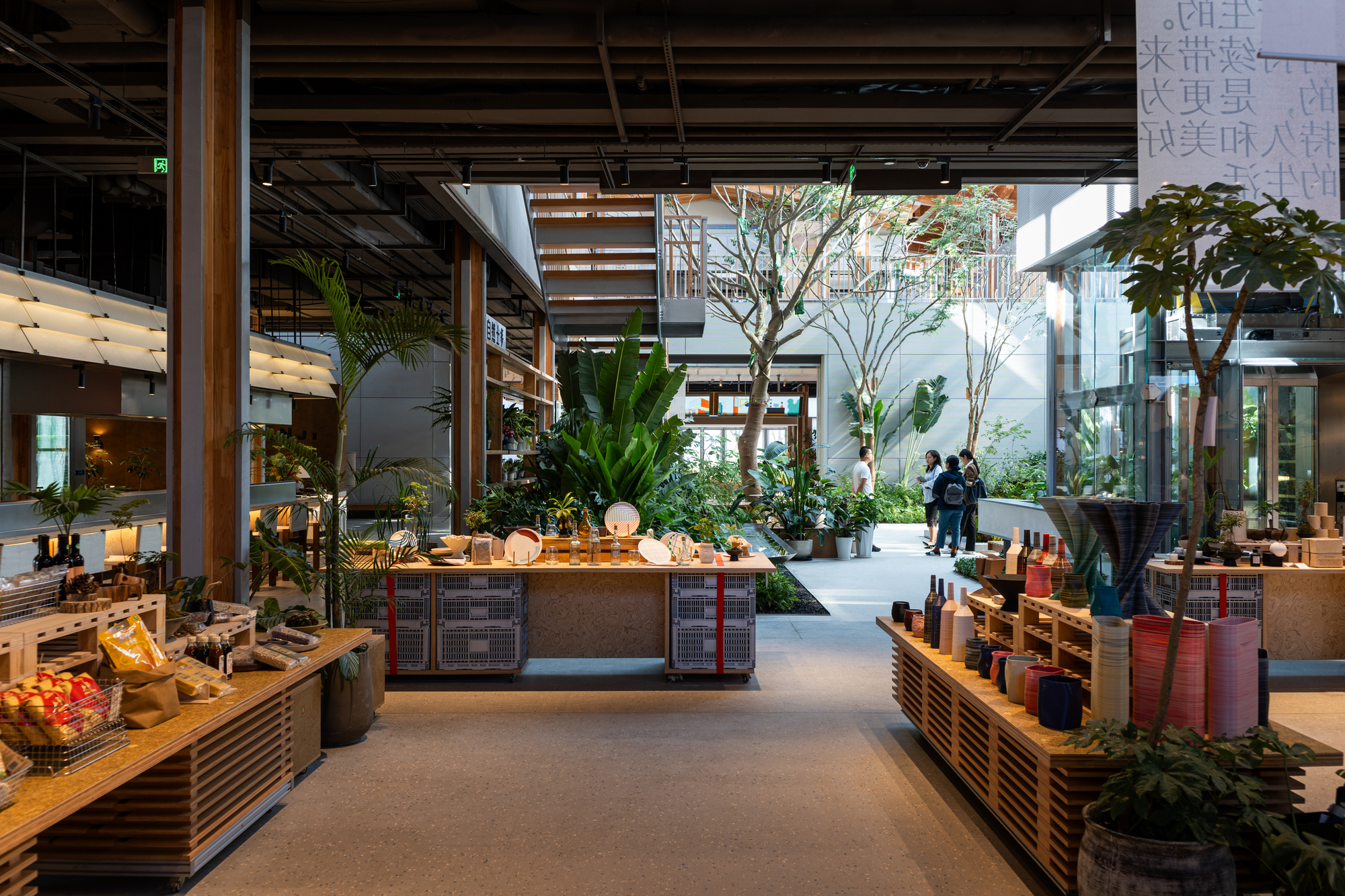 Retail interior space with central display counter, indoor trees, potted plants and exposed timber ceiling