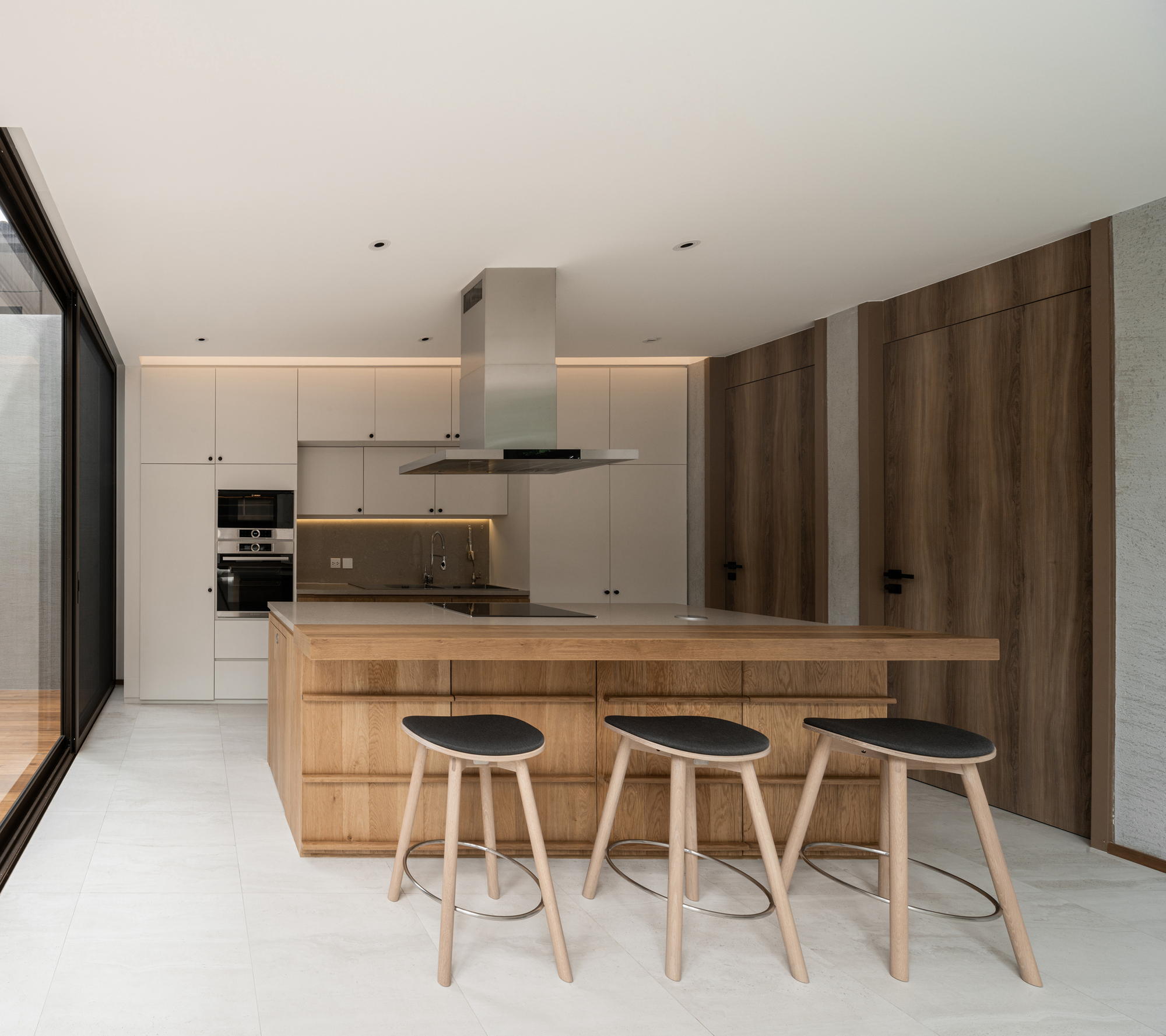 Kitchen with timber island, three bar stools, and white cabinetry with strip lighting