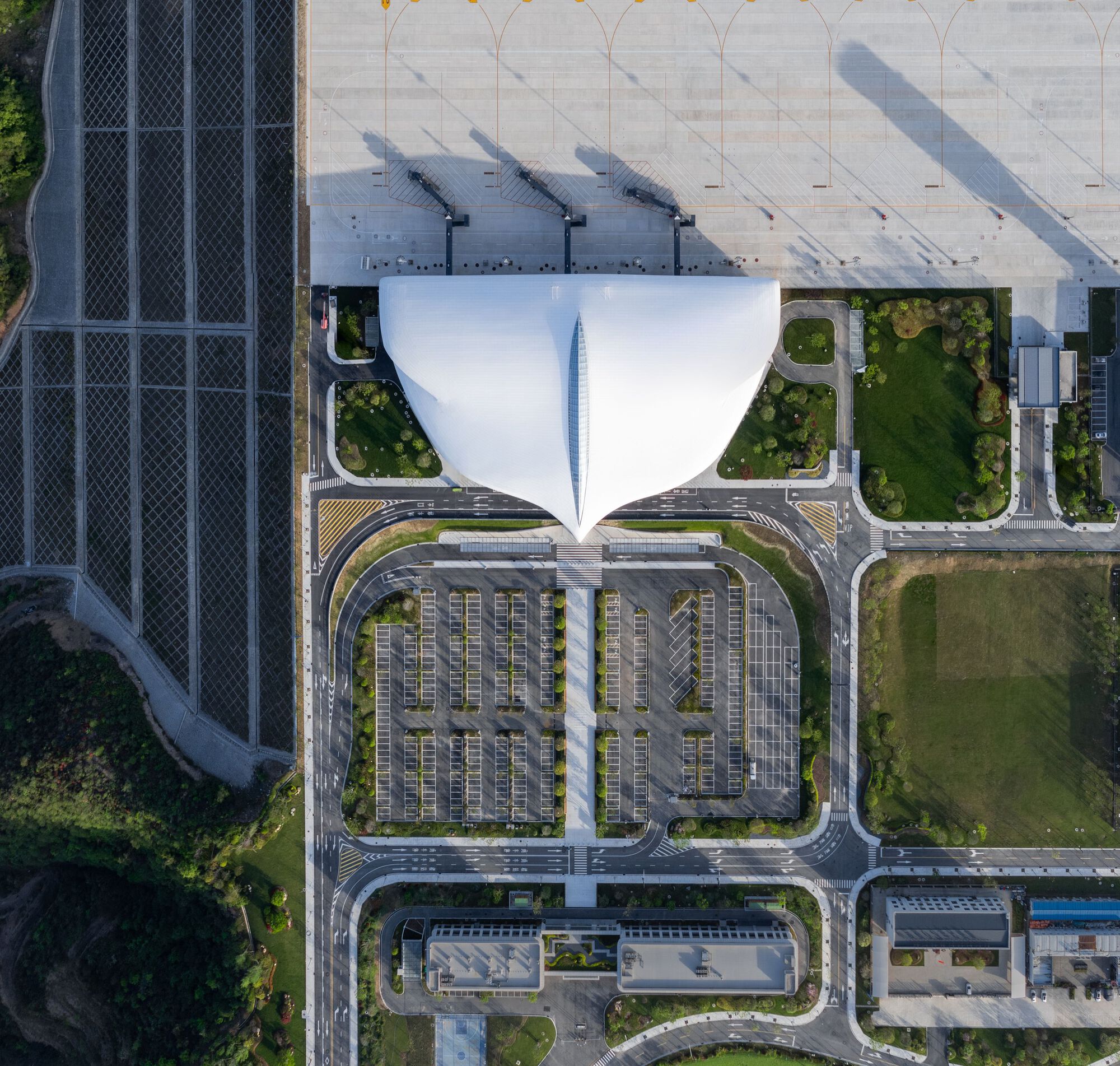 Aerial view of the twin-lobed white roof over surrounding parking lots and landscaped beds