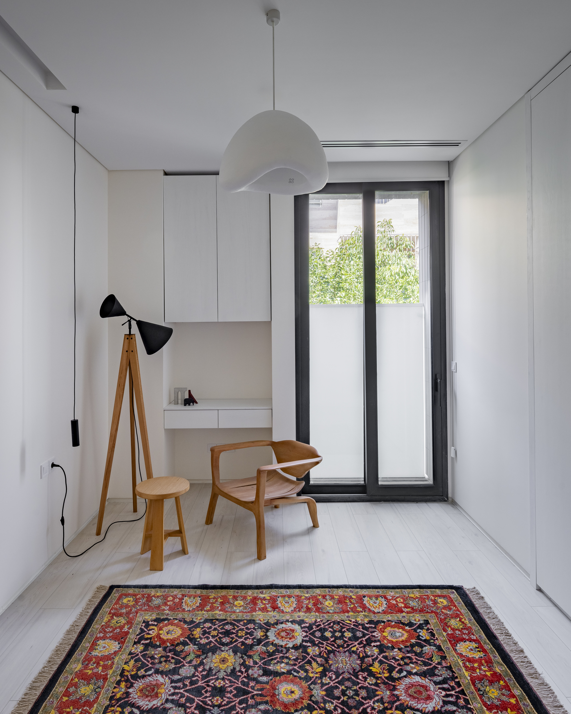 Study nook with built-in desk and timber chair beneath spherical pendant and tripod floor lamp