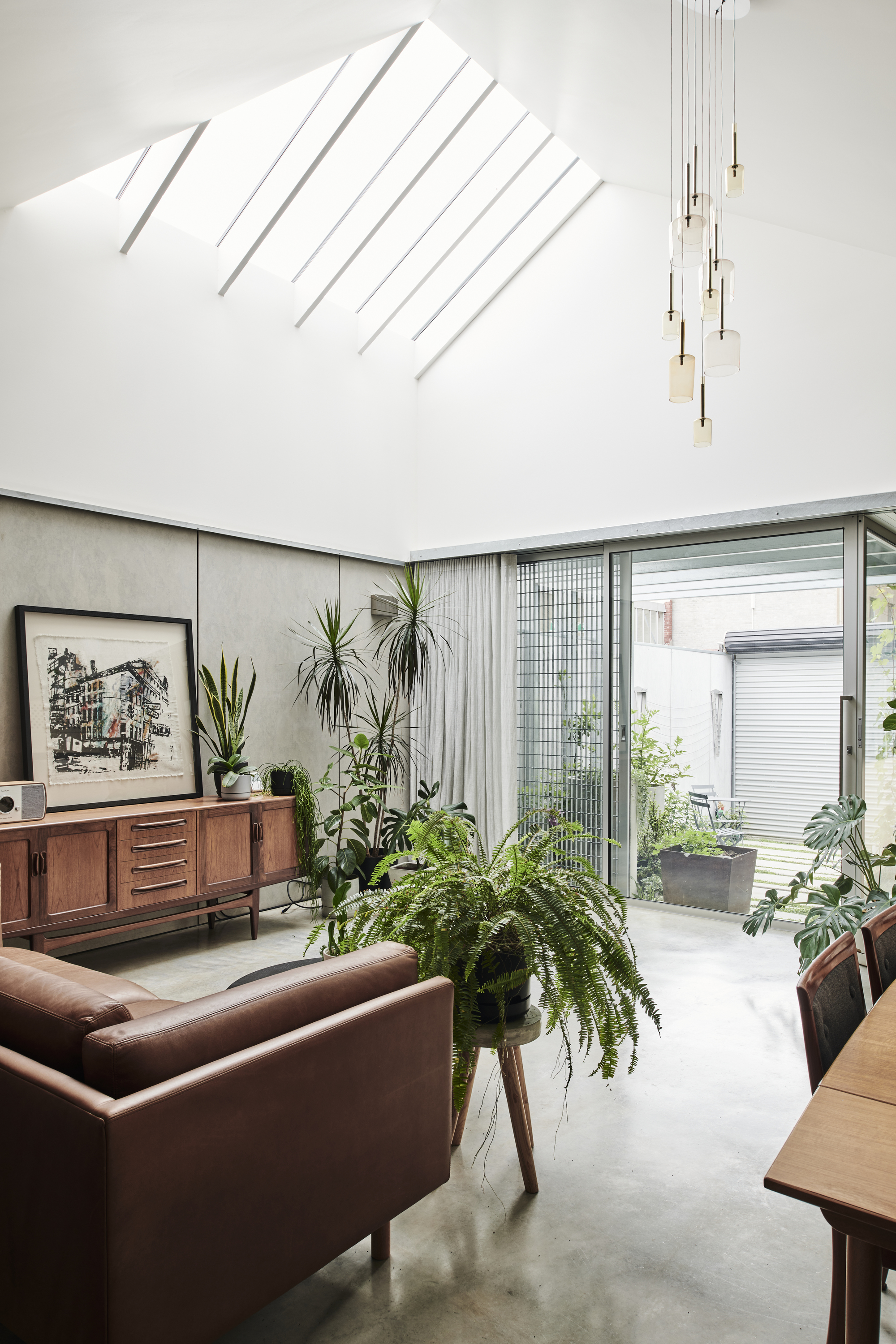 Living room with vaulted ceiling and angled skylights casting diagonal shadow patterns on white walls